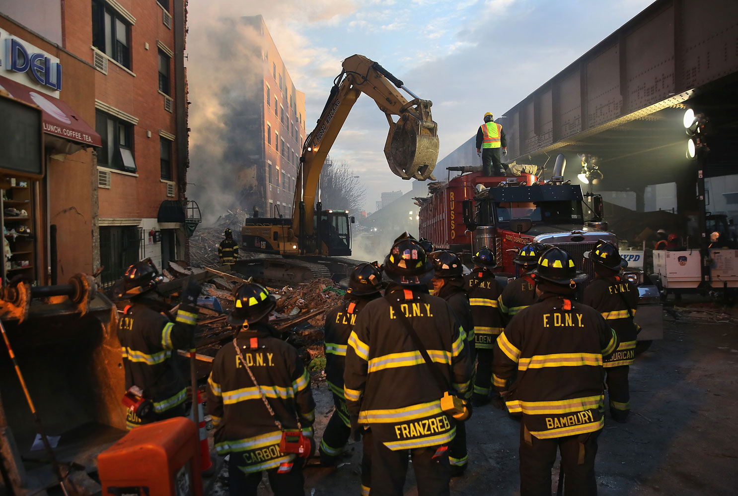NEW YORK, NY - MARCH 13: Firemen watch as work crews remove debris from the site of an explosion in East Harlem on March 13, 2014 in New York City. At least 7 people were killed, according to reports, in Wednesday's explosion which collapsed two building
