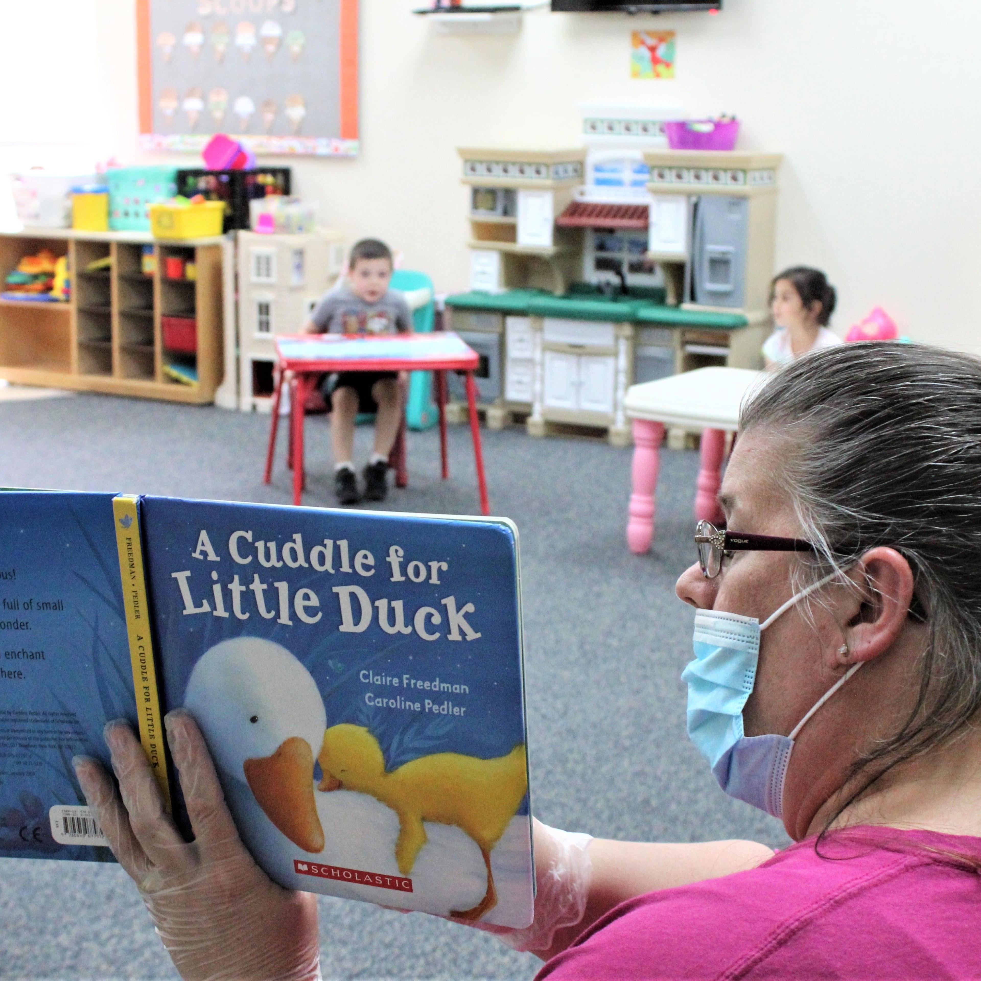 Daycare provider Darlene Mount reads to socially distanced children at a New Jersey YMCA