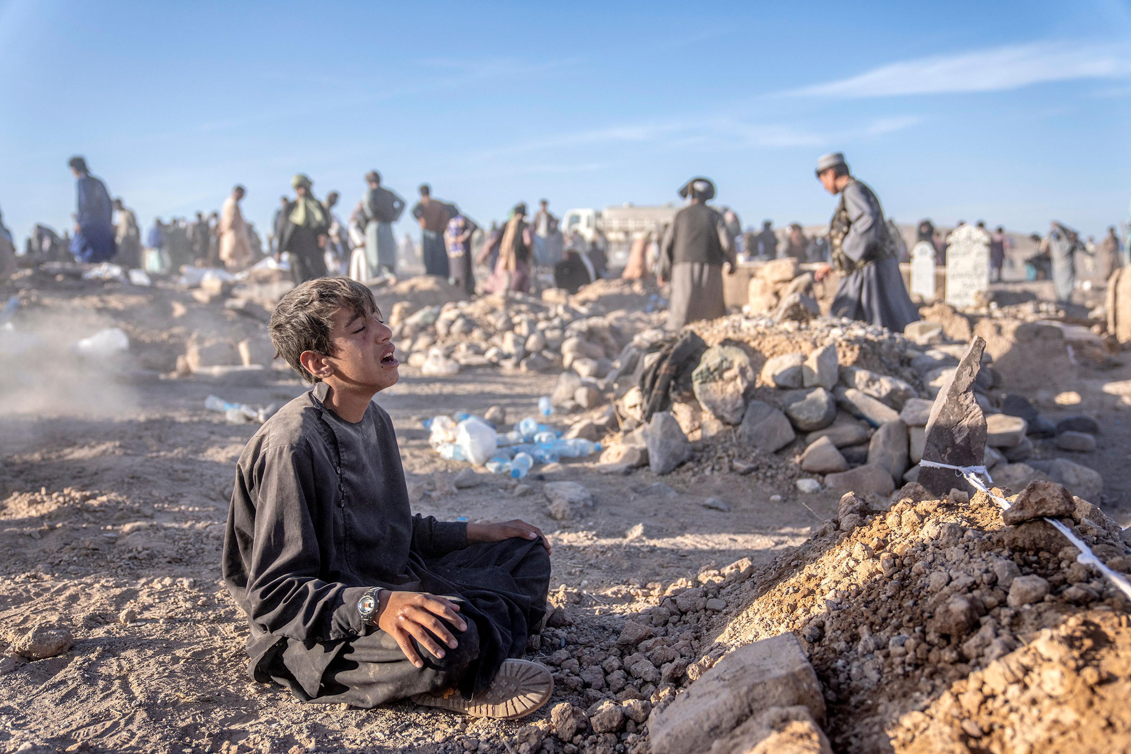 An Afghan boy mourns next to the grave of his little brother who died due to an earthquake, in Zenda Jan district in Herat province, western of Afghanistan, on Oct. 9.