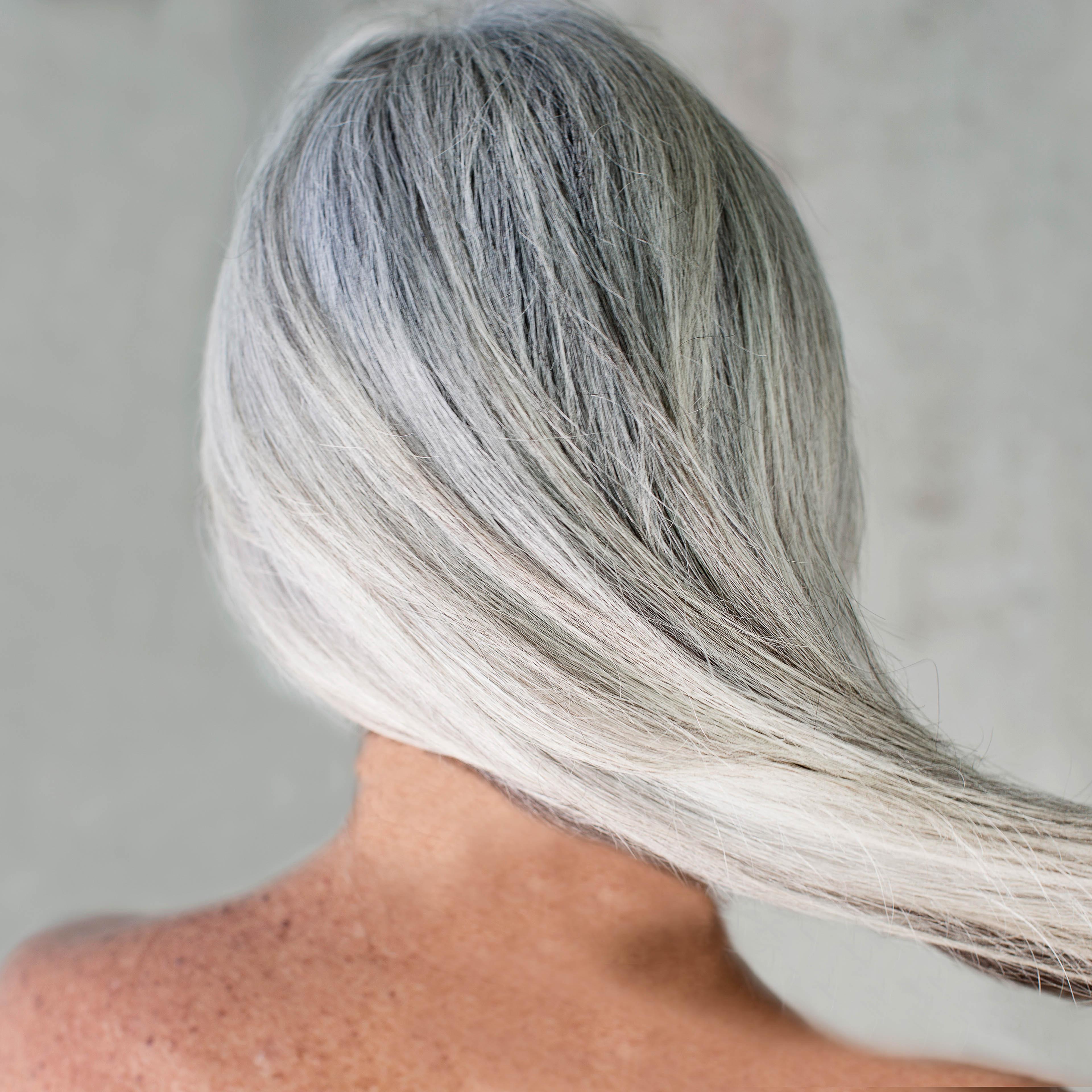 Rear view of bare shouldered mature woman with long grey hair