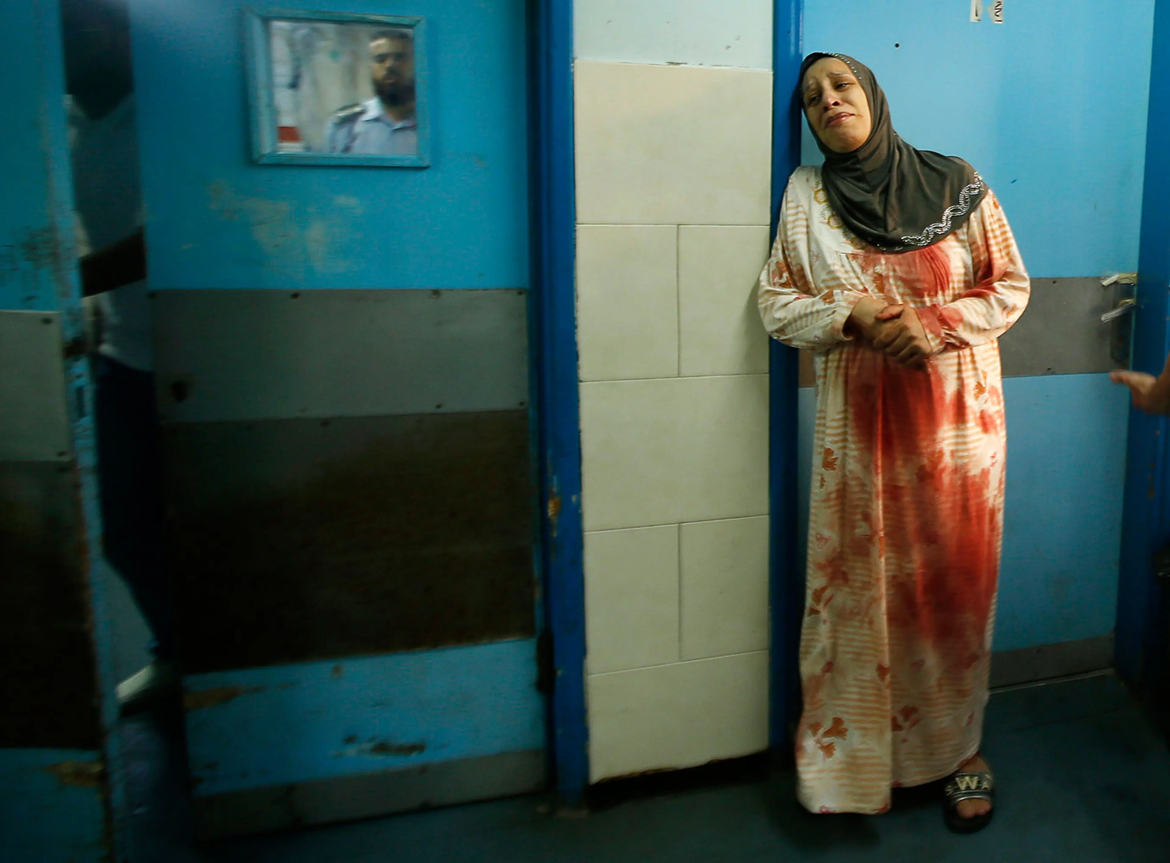 A Palestinian woman wearing clothes stained with the blood of other relatives, who medics said were wounded in Israeli shelling, cries at a hospital in Gaza City