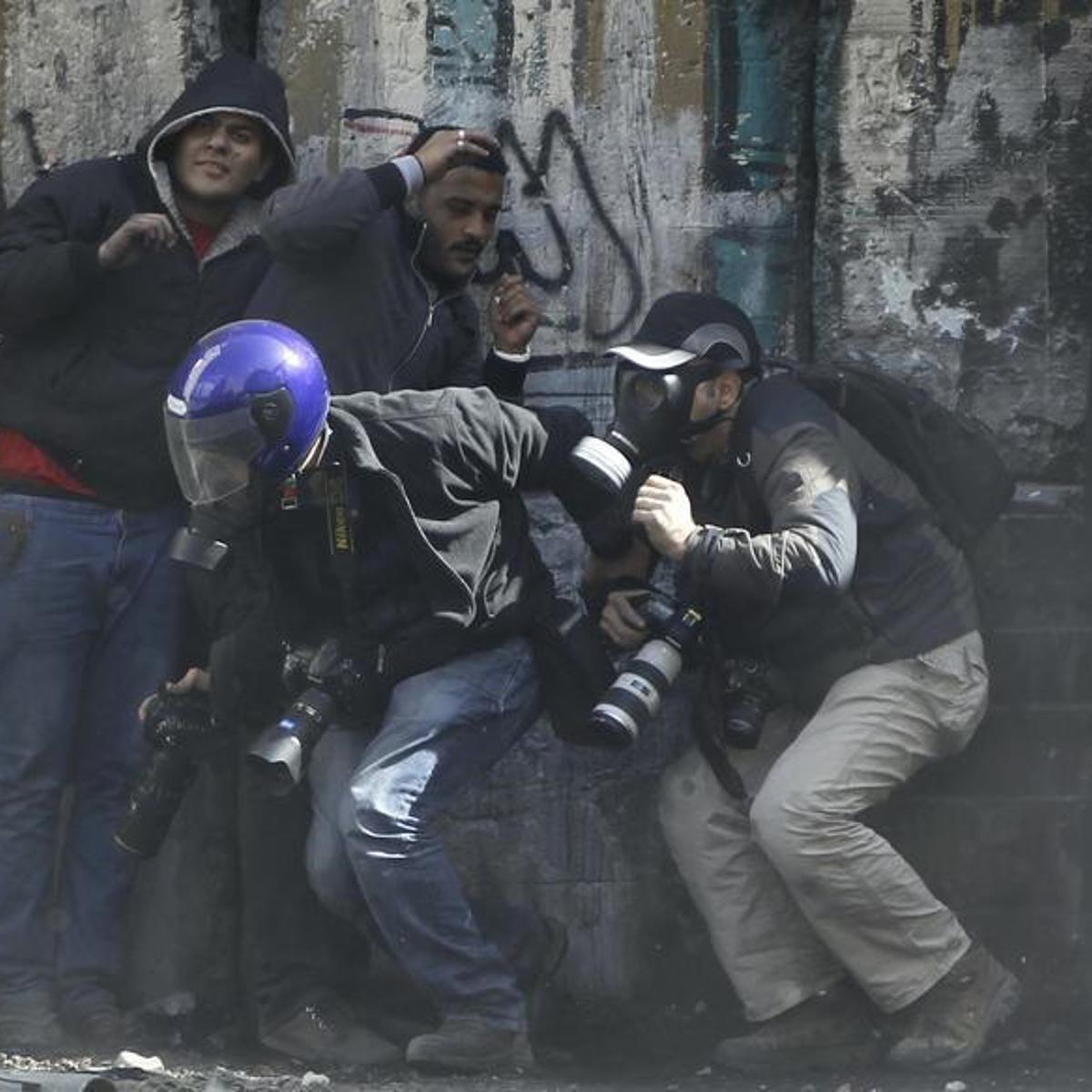 Photographers cower as protesters throw stones towards riot police along Sheikh Rihan street near Tahrir Square in Cairo January 25, 2013.