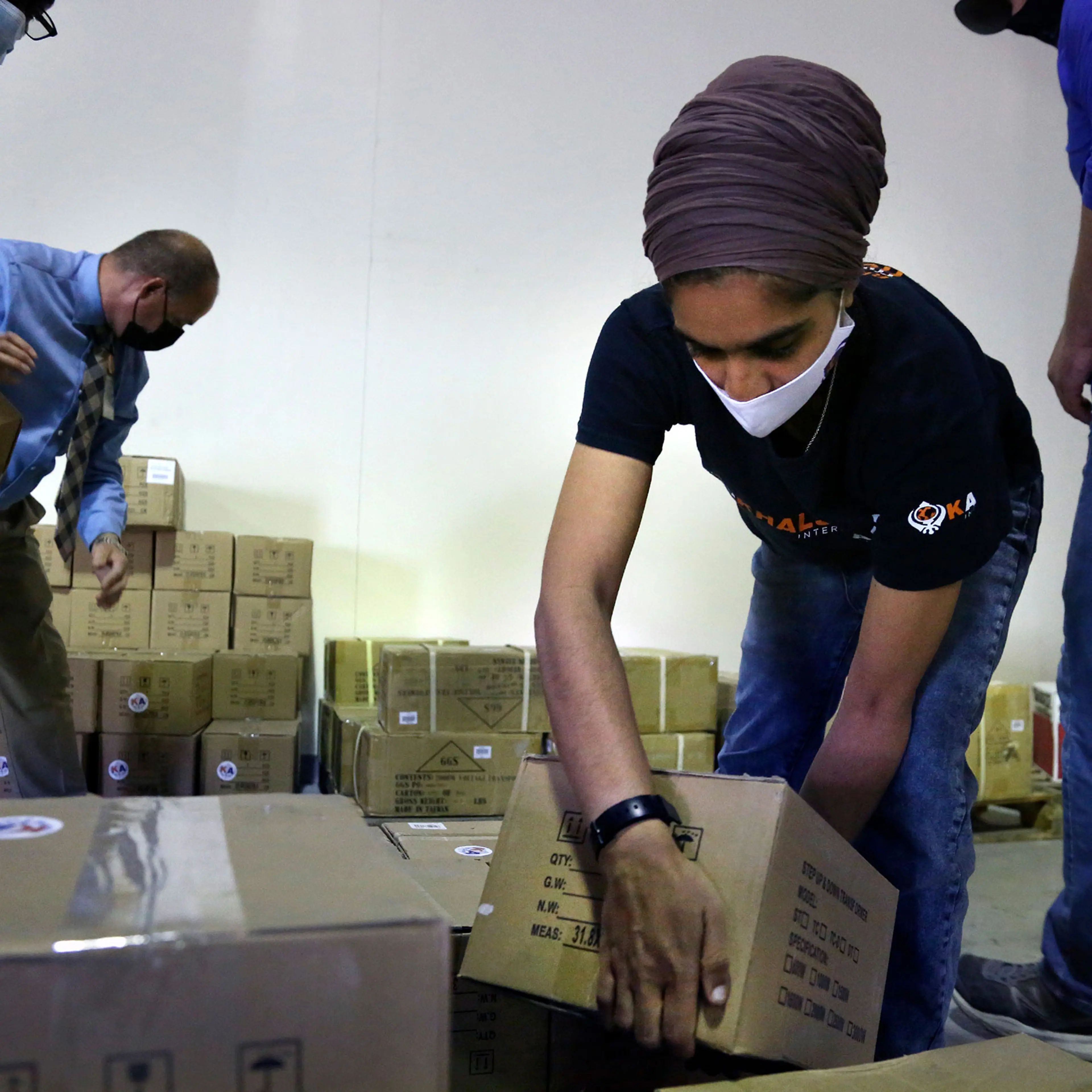Tim Williams, warehouse assistant for Medisys, Ray Fredericks, assistant director for Medisys, Dr. Abhu Kaur with Khalsa Aid, and Michael Stack, healthcare account representative for Grainger, load dozens of electrical transformers onto a pallet to be sh