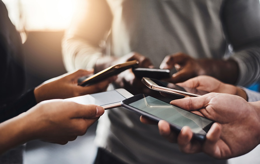 Shot of a group of unrecognizable people using their mobile phones together