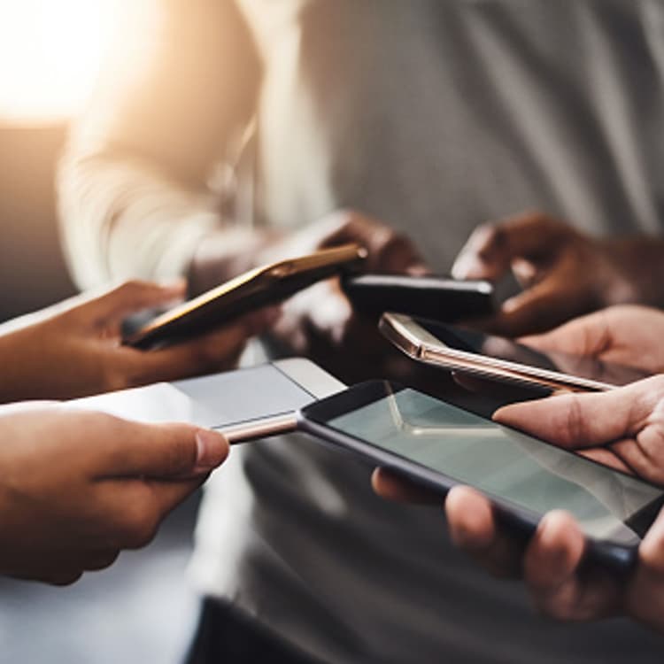 Shot of a group of unrecognizable people using their mobile phones together