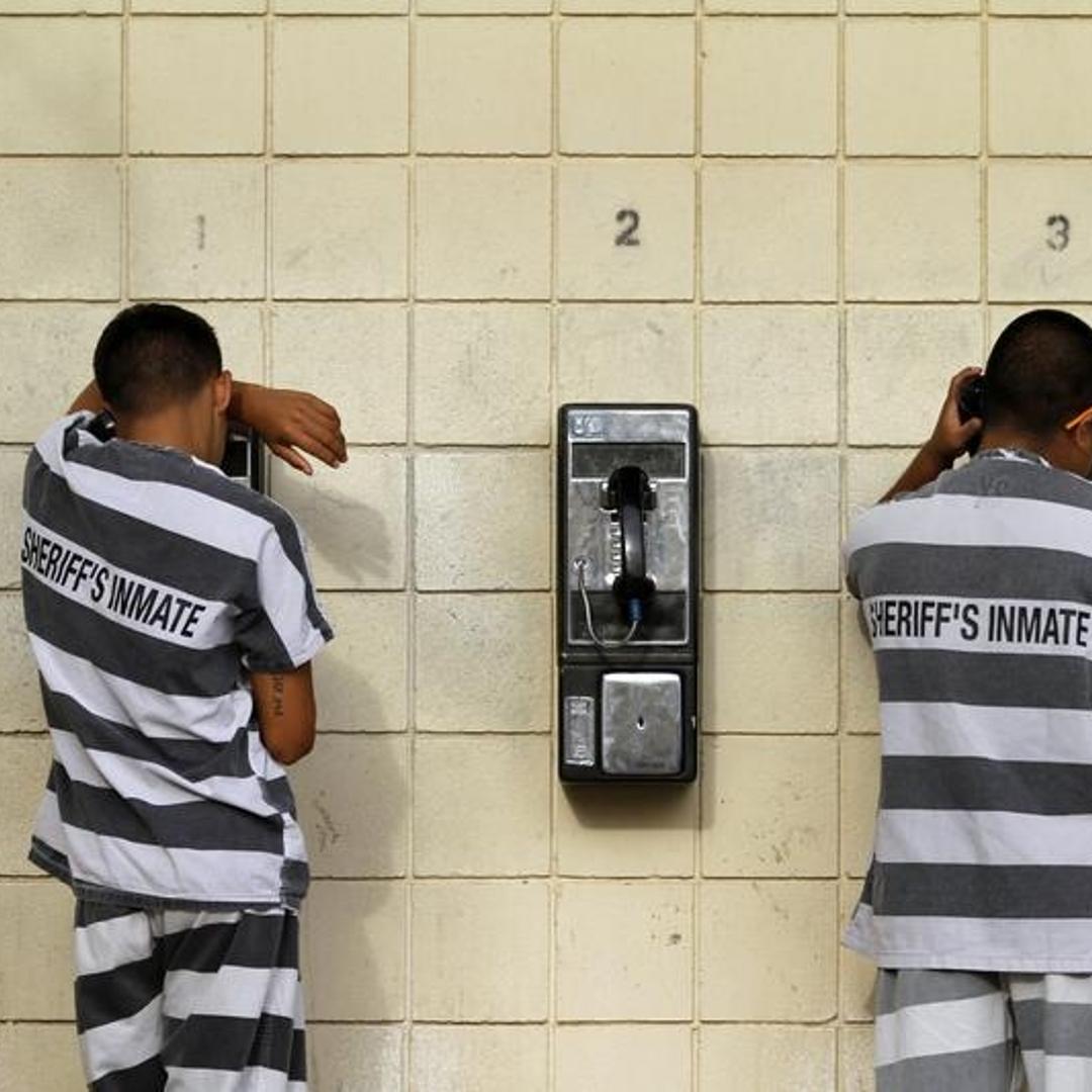 Inmates serving a jail sentence make a phone call at Maricopa County's Tent City jail in Phoenix