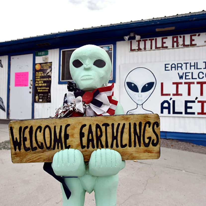 An alien-like statue displays a sign welcoming guests to the Little A'le' Inn restaurant and gift shop in Rachel, Nevada on July 22, 2019.