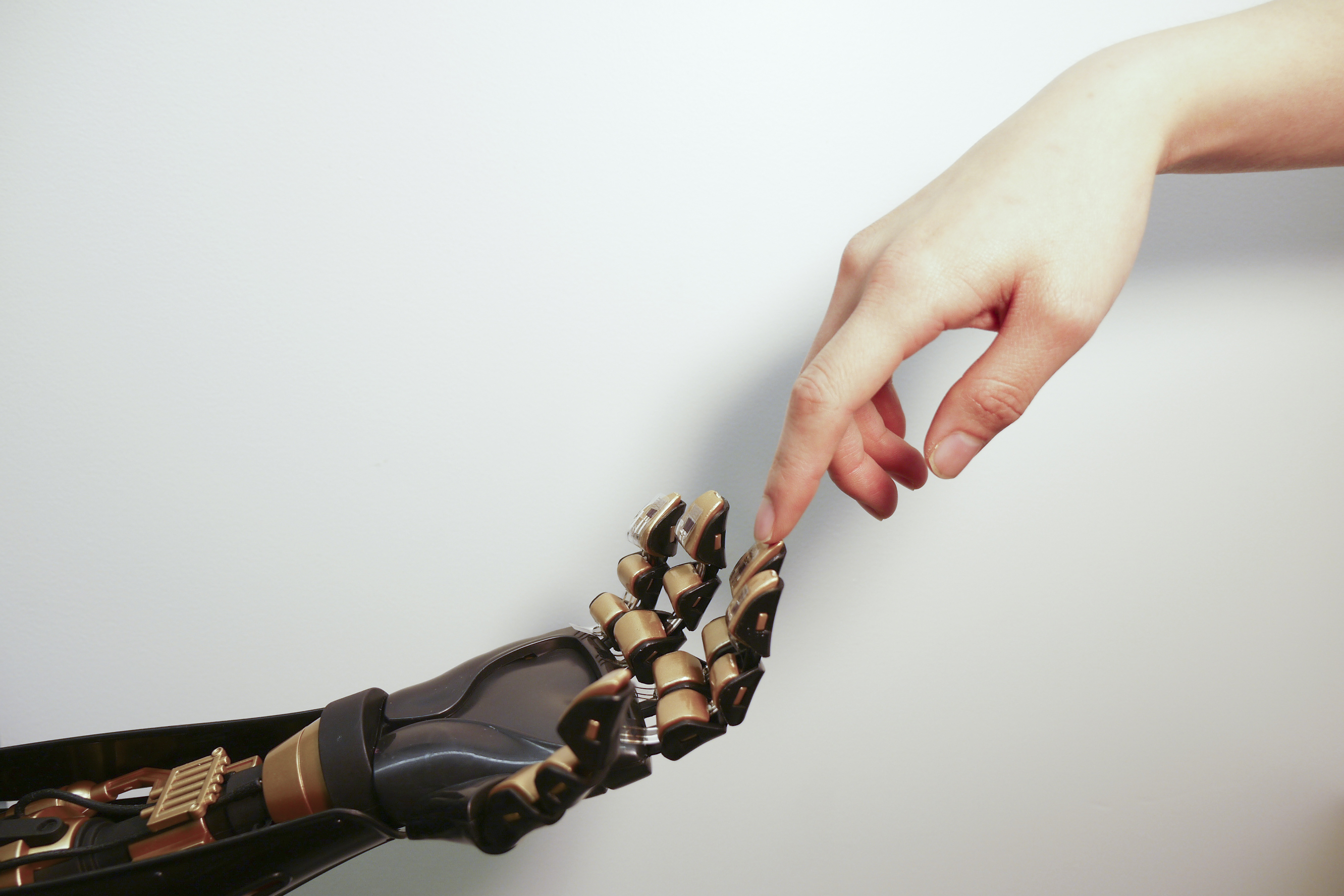 Human finger touches robotic finger. The transparent plastic and black device on the golden “fingertip” is the skin-like sensor developed by Stanford engineers. This sensor can detect pressure and transmit that touch sensation to a nerve cell. The goal i