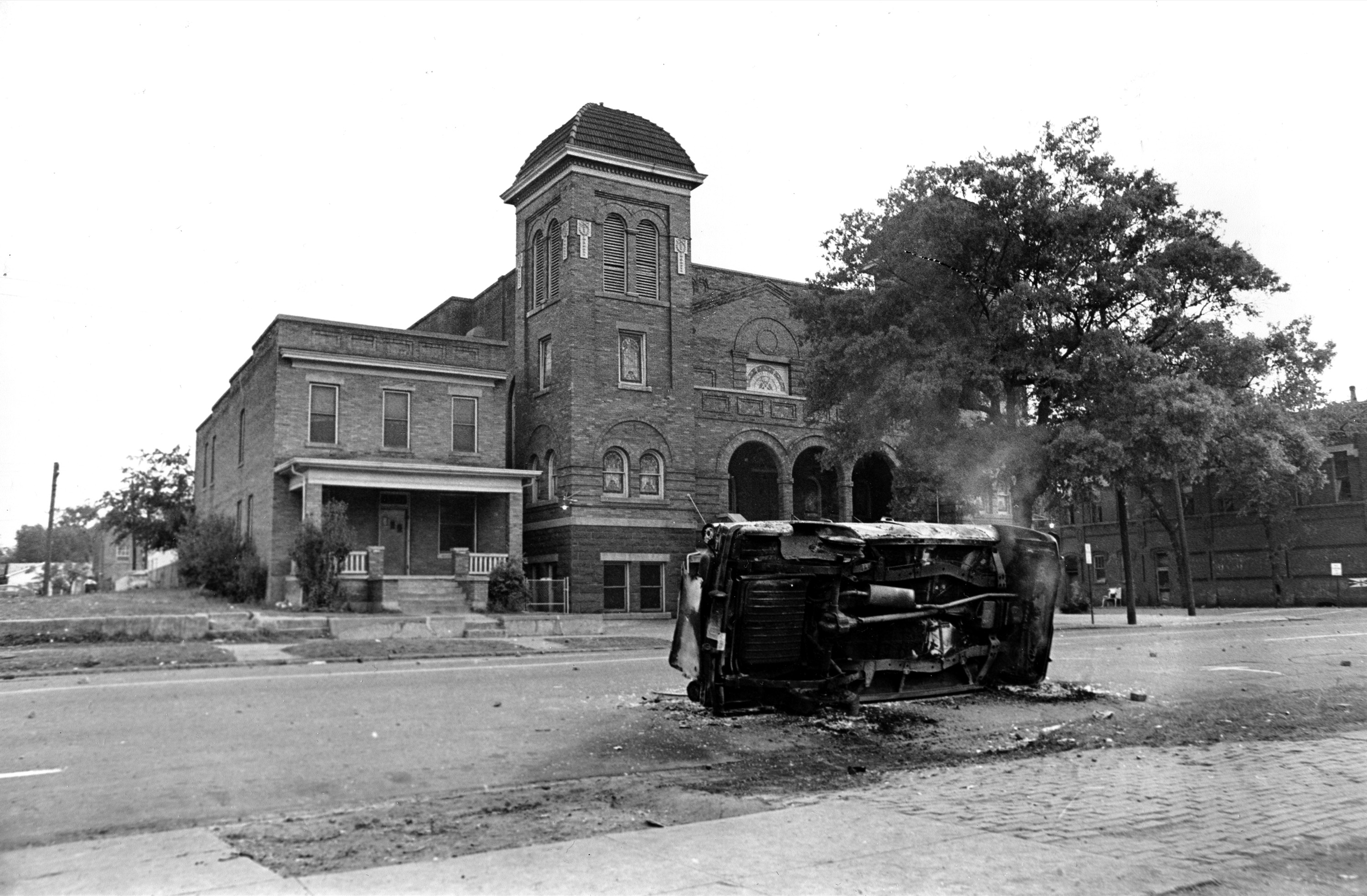 A burned taxicab turned on its side still smoulders in the aftermath of two bombings and violence that erupted in the black neighborhood in Birmingham, Ala on May 12, 1963.
