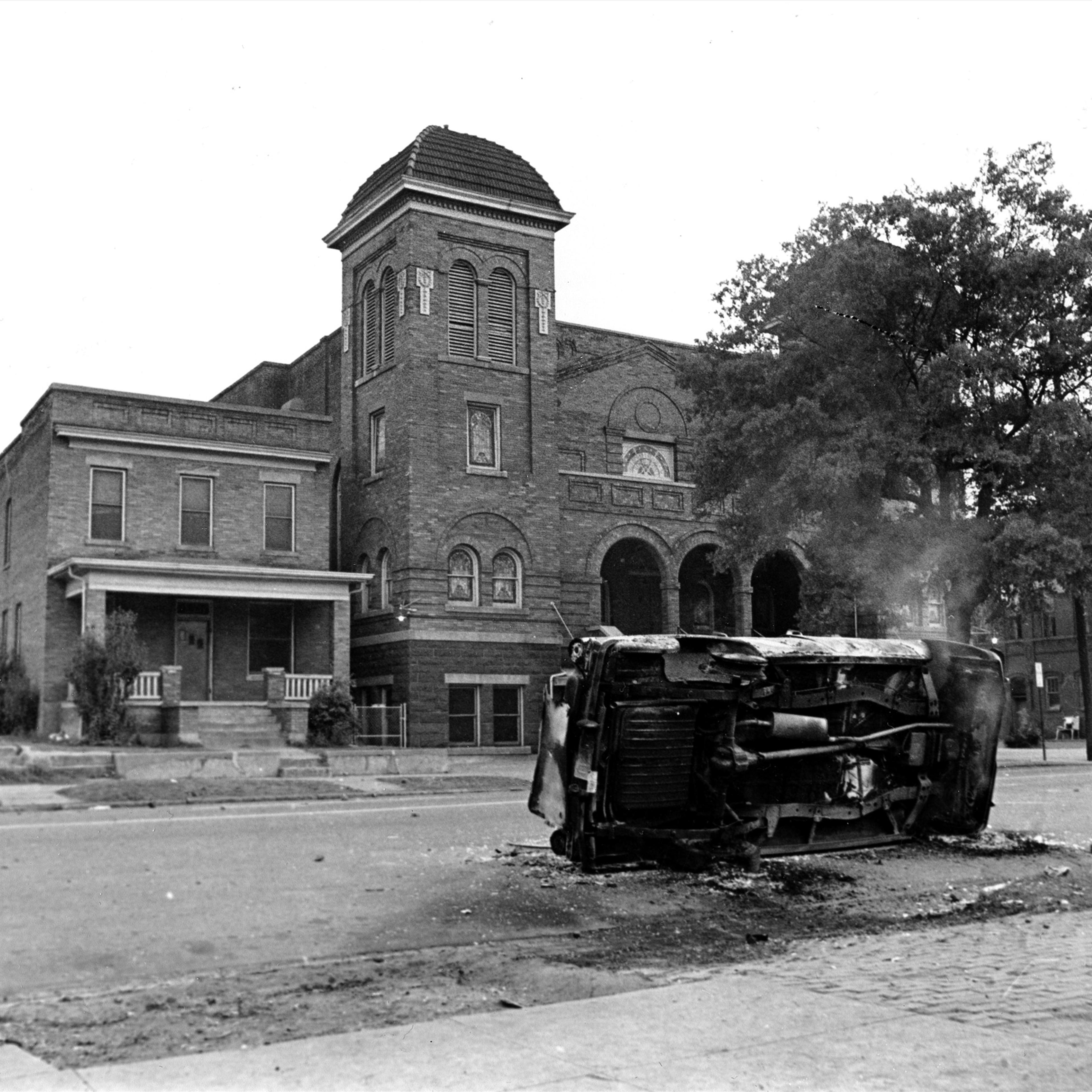 A burned taxicab turned on its side still smoulders in the aftermath of two bombings and violence that erupted in the black neighborhood in Birmingham, Ala on May 12, 1963.