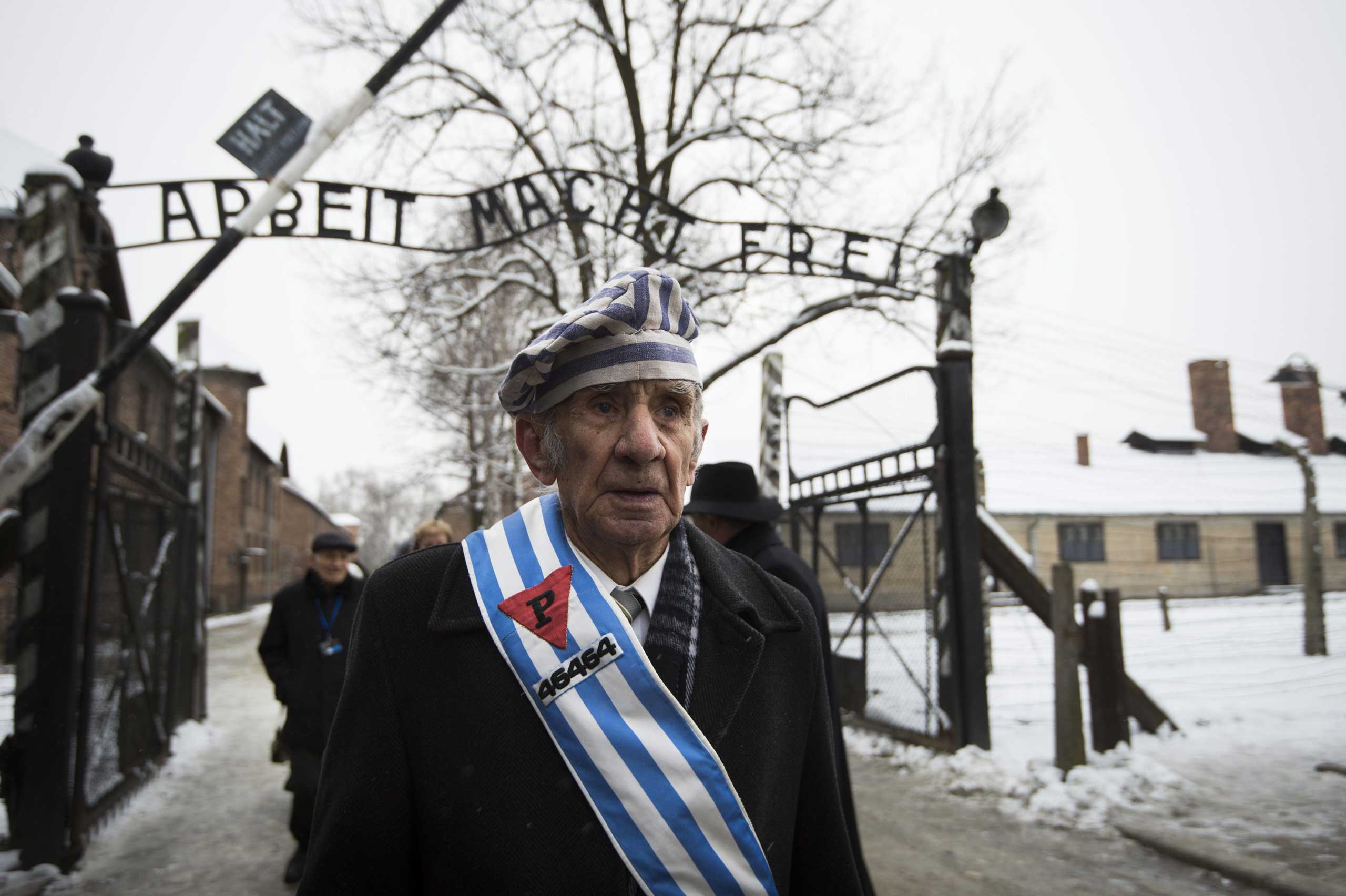 Auschwitz survivor Miroslaw Celka walks out the gate with the sign saying "Work makes you free" after paying tribute to fallen comrades at the "death wall" execution spot in the former Auschwitz concentration camp in Oswiecim, Poland, on the 70th anniver