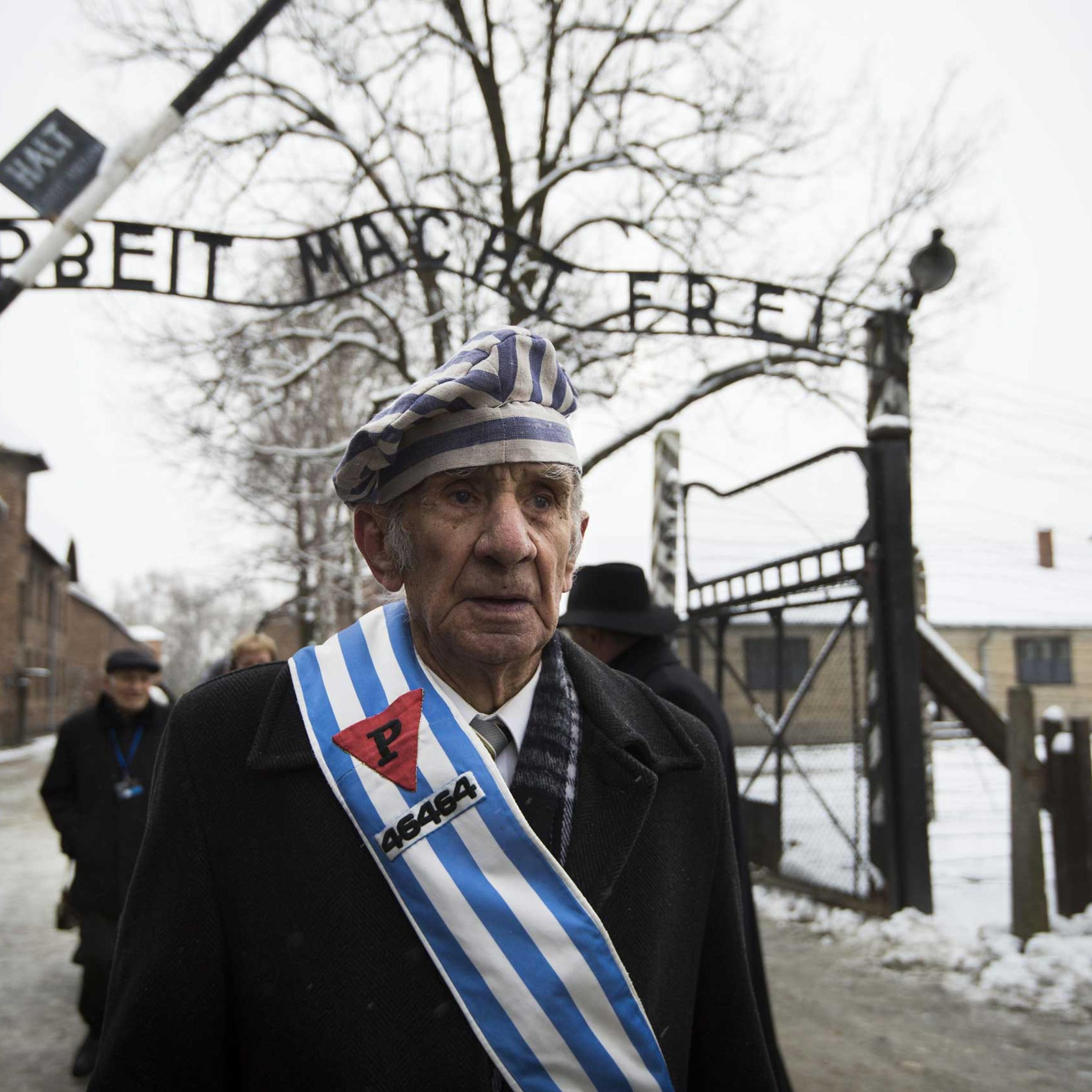 Auschwitz survivor Miroslaw Celka walks out the gate with the sign saying "Work makes you free" after paying tribute to fallen comrades at the "death wall" execution spot in the former Auschwitz concentration camp in Oswiecim, Poland, on the 70th anniver