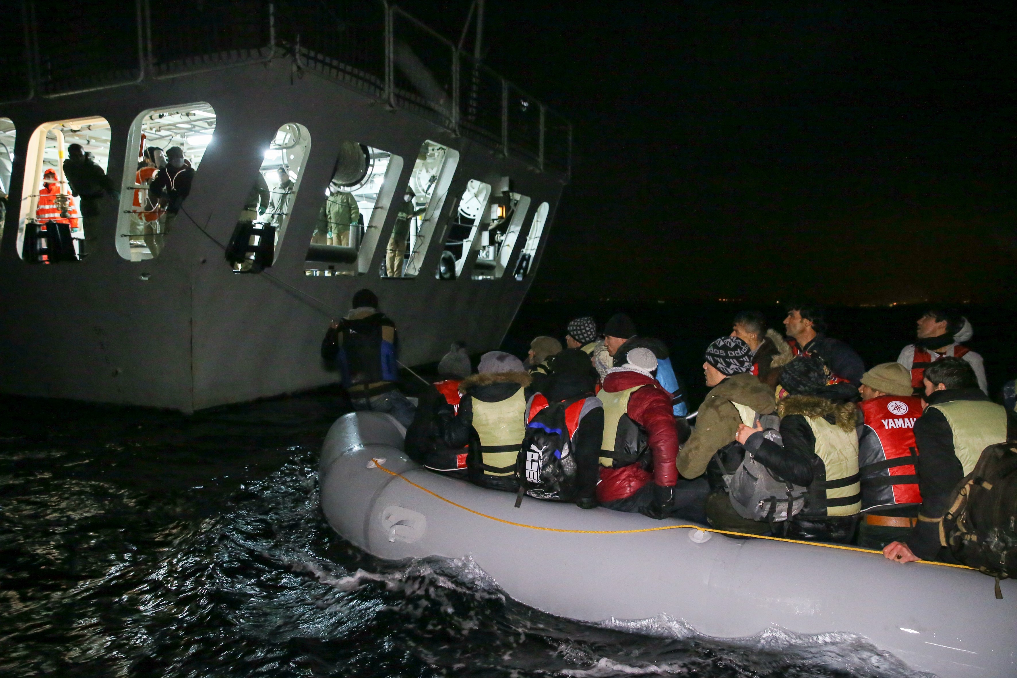 Turkish coast guards pull a refugee boat into a Turkish Coast Guard ship during a rescue operation for the asylum seeker refugees who were illegally trying to reach Greece through the Aegean Sea with a overloaded inflatable boat, on the shores of Turkey'