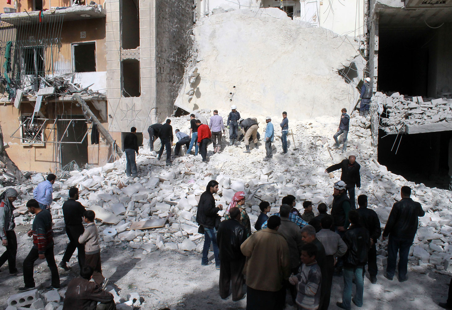 Syrians look at the destruction following an airstrike by government forces on the northern Syrian city of Aleppo on March 5, 2014.