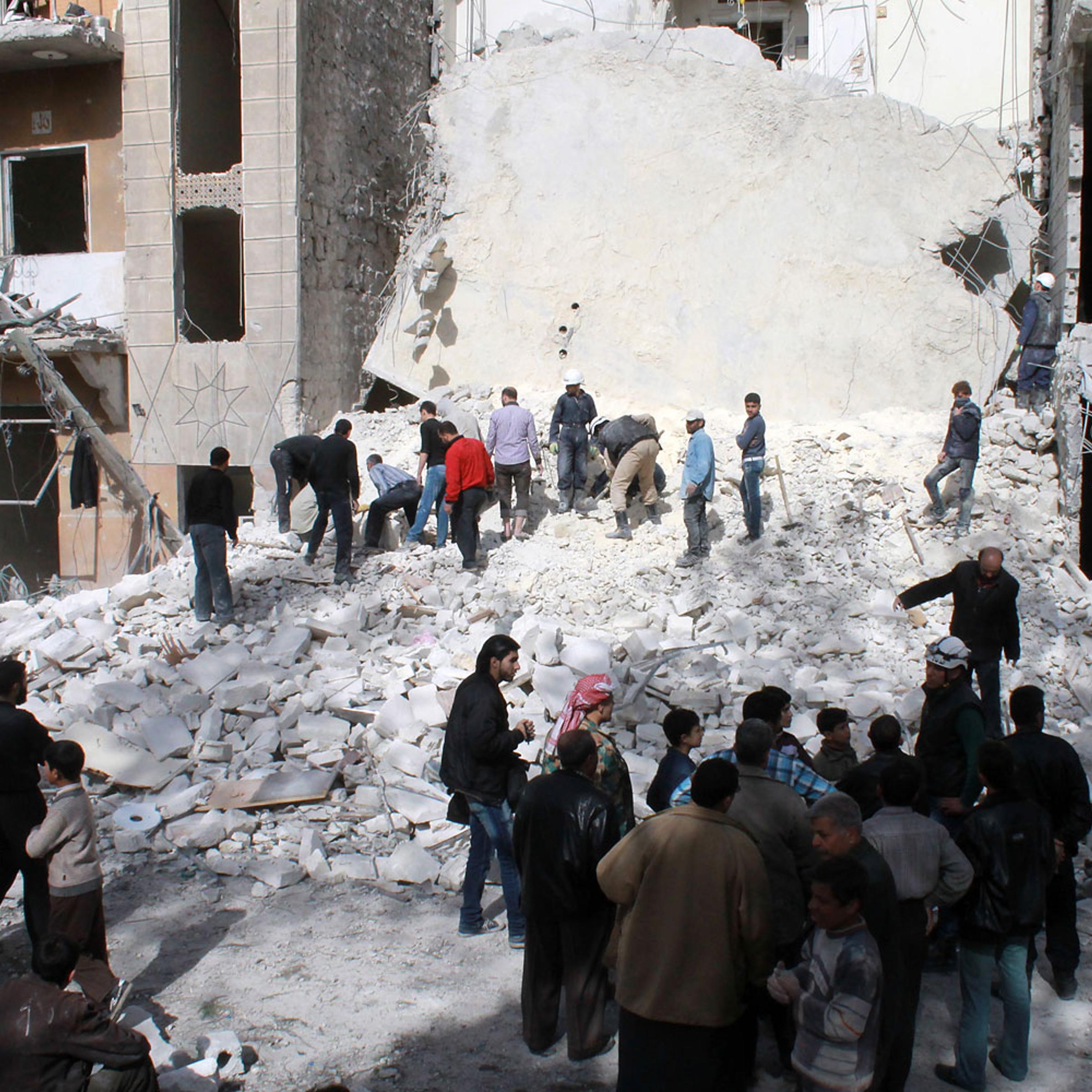 Syrians look at the destruction following an airstrike by government forces on the northern Syrian city of Aleppo on March 5, 2014.