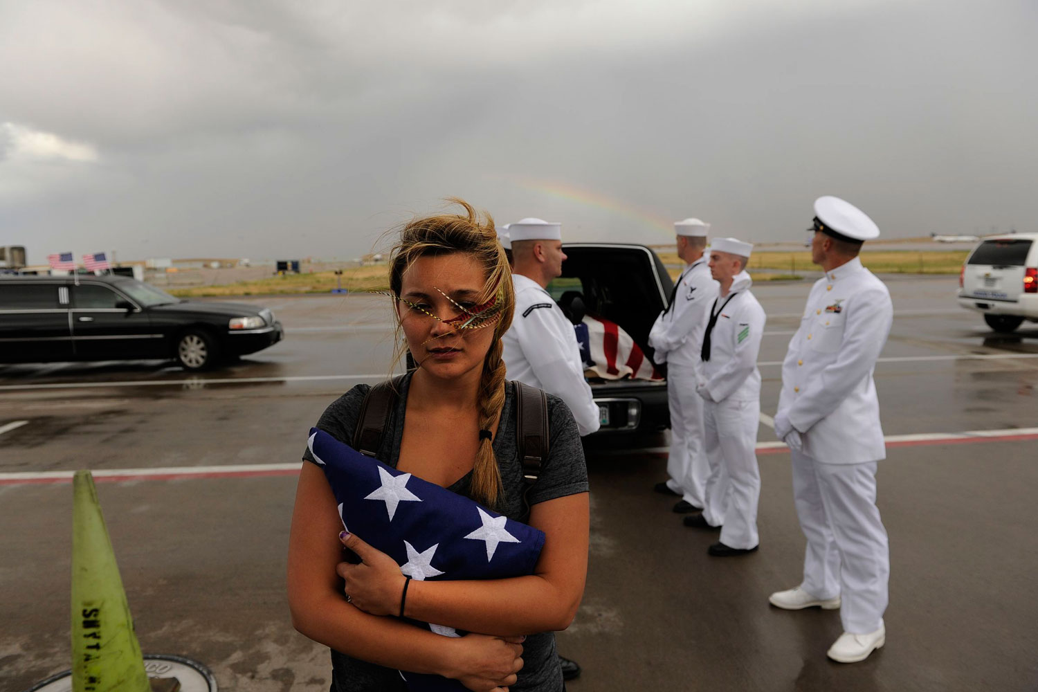 <b>No More Shooting Massacres</b>
<br><br>July 27, 2012. A rainbow appears behind Chantel Blunk, wife of Jonathan Blunk, as the flag-draped casket bearing her husband's remains is loaded onto a plane at Denver International Airport. Blunk, a five-year U.S. Navy veteran, was killed in the July 20 <i>Dark Knight Rises</i> shooting massacre in Aurora, Colorado.  