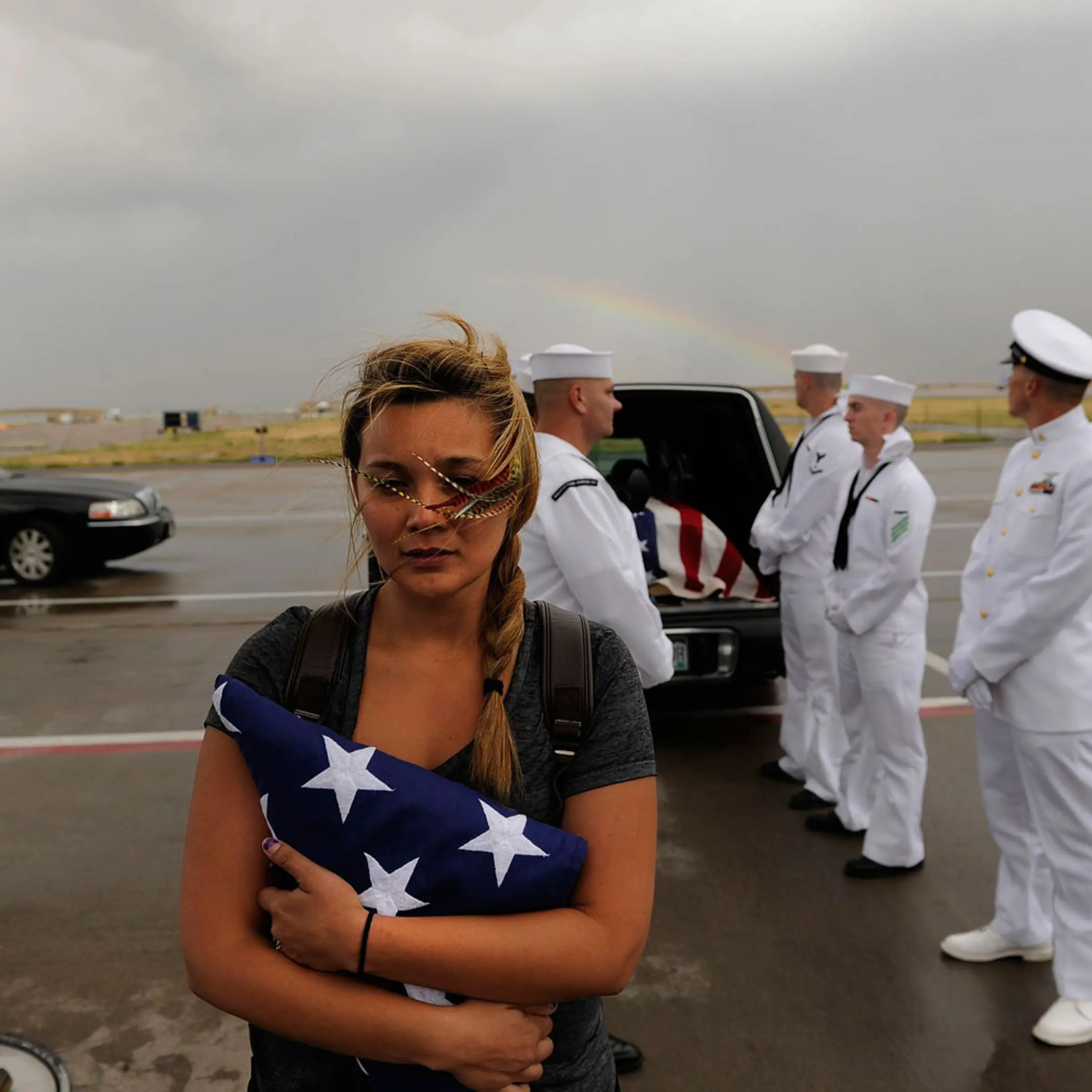<b>No More Shooting Massacres</b>
<br><br>July 27, 2012. A rainbow appears behind Chantel Blunk, wife of Jonathan Blunk, as the flag-draped casket bearing her husband's remains is loaded onto a plane at Denver International Airport. Blunk, a five-year U.S. Navy veteran, was killed in the July 20 <i>Dark Knight Rises</i> shooting massacre in Aurora, Colorado.