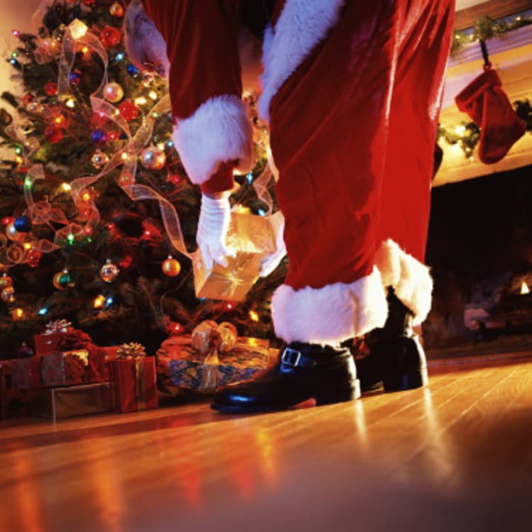 Santa Claus placing gift under tree