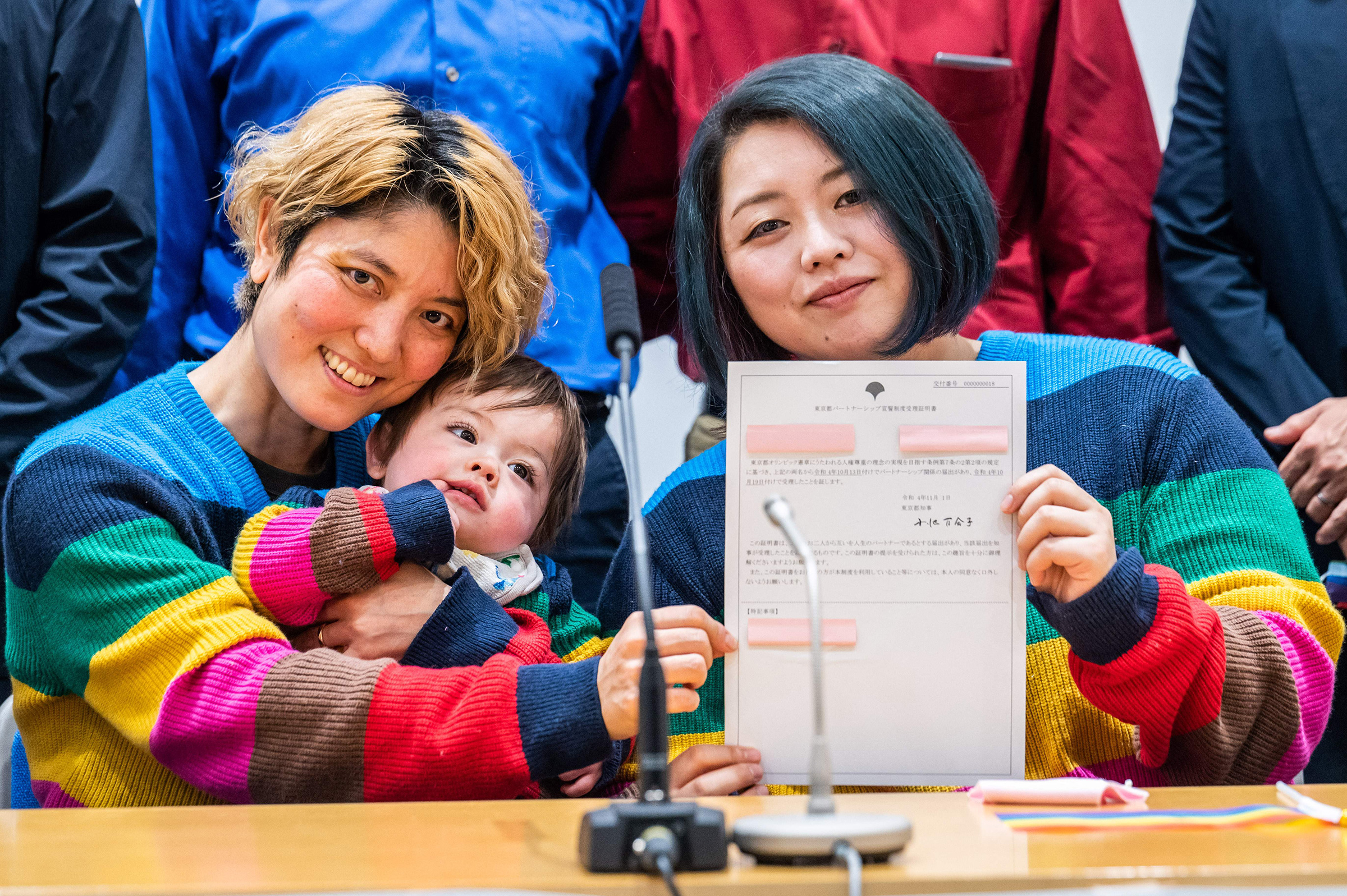 Mamiko Moda (L) and her partner Satoko Nagamura, with their son, hold a same-sex partnership certificate as they pose for a photograph after a press conference at the Tokyo Metropolitan Government building on Nov. 1. 