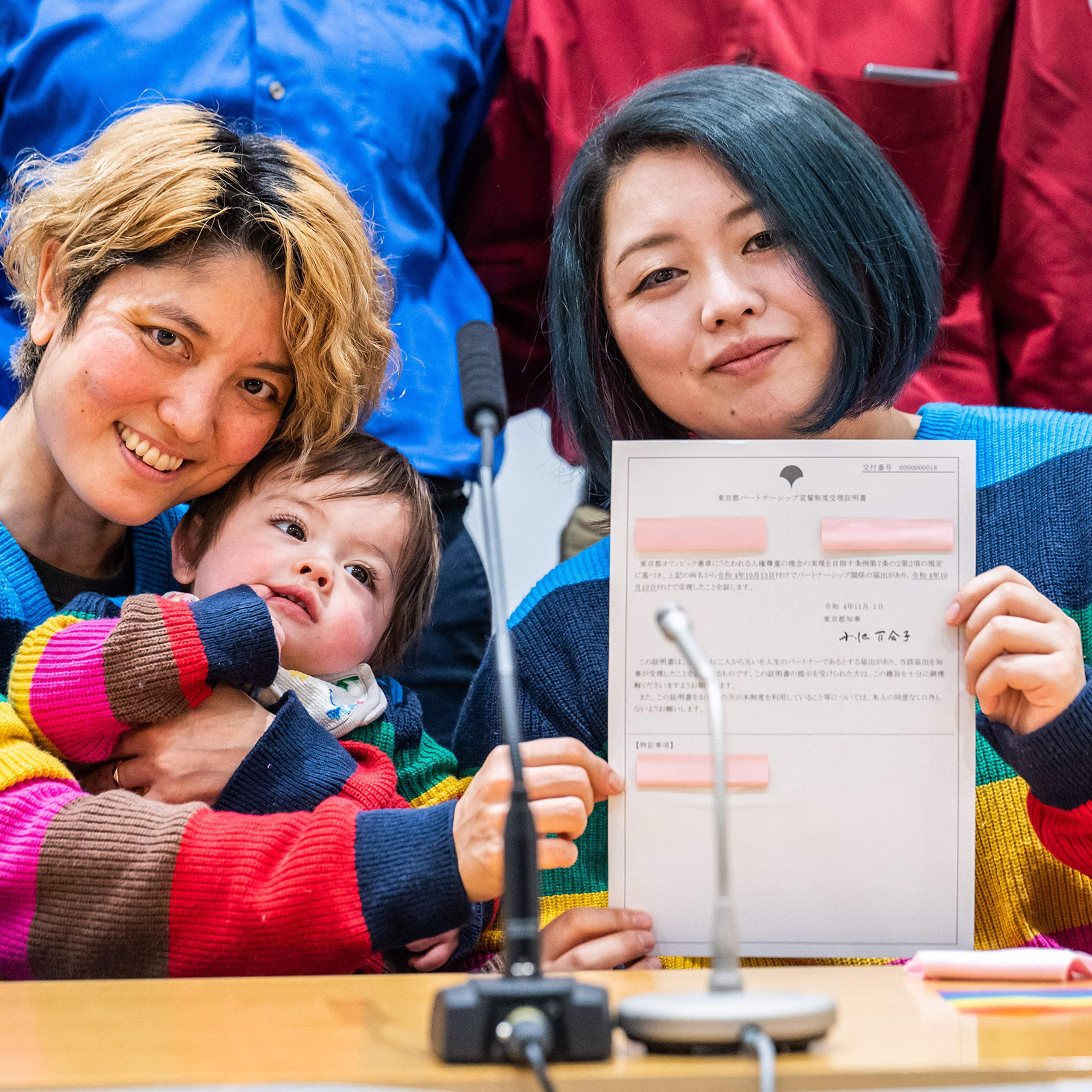 Mamiko Moda (L) and her partner Satoko Nagamura, with their son, hold a same-sex partnership certificate as they pose for a photograph after a press conference at the Tokyo Metropolitan Government building on Nov. 1.