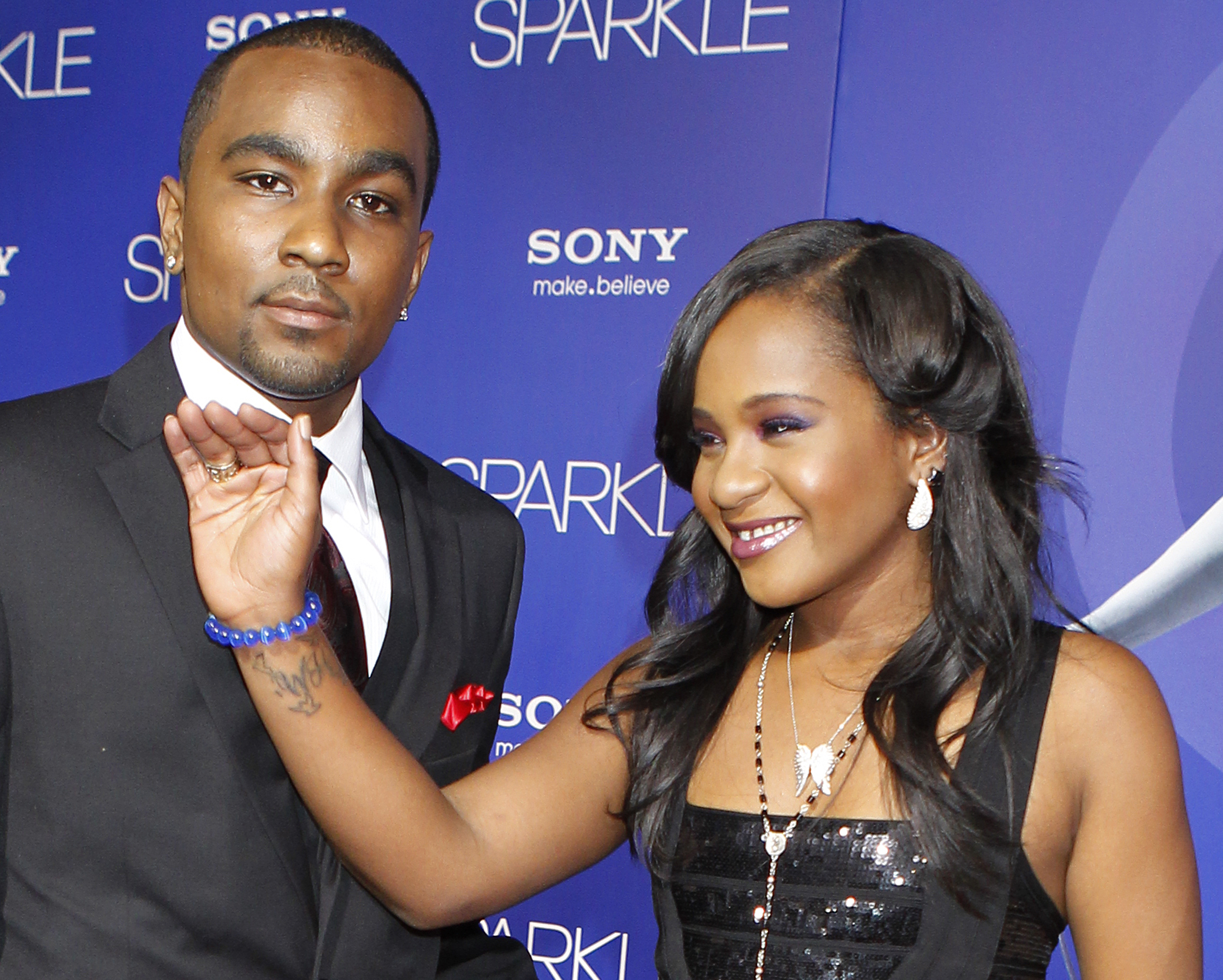 Bobbi Kristina Brown reveals a tattoo with the initials "W H" as she waves while arriving with boyfriend Nick Gordon at the premiere of the new film "Sparkle" starring Jordin Sparks and the late Whitney Houston in Hollywood