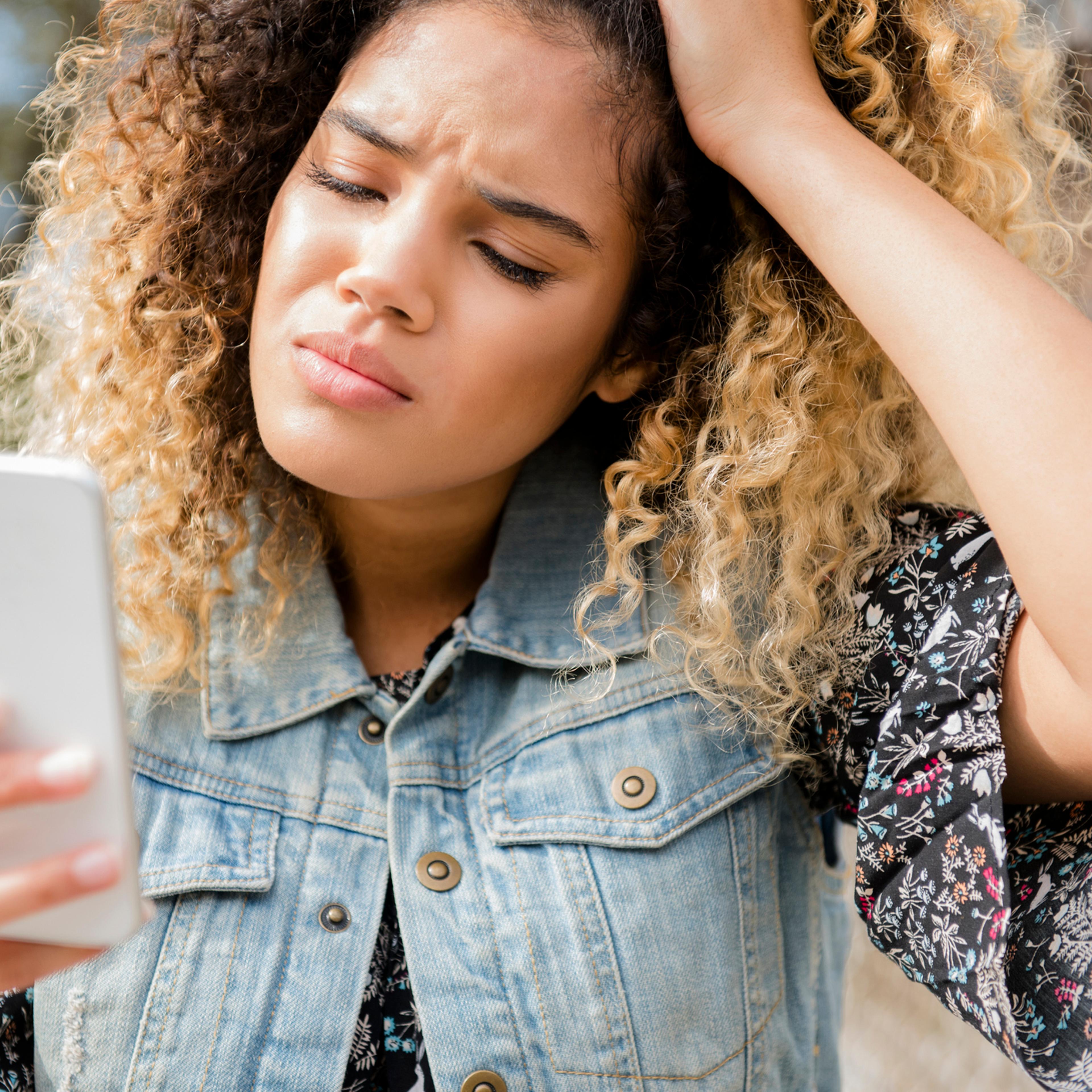 Unhappy Mixed Race woman texting on cell phone