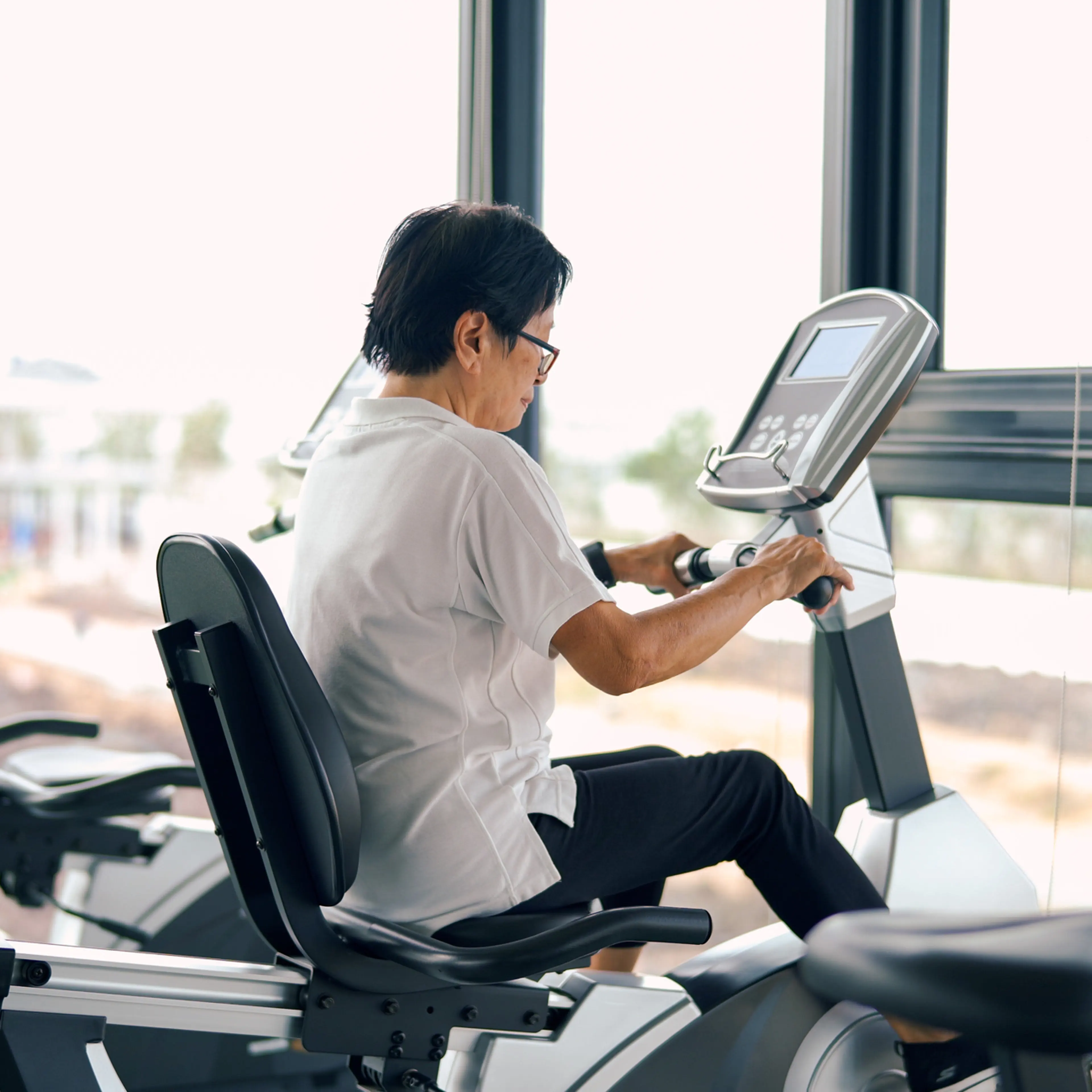 Senior woman riding on stationary at gym.