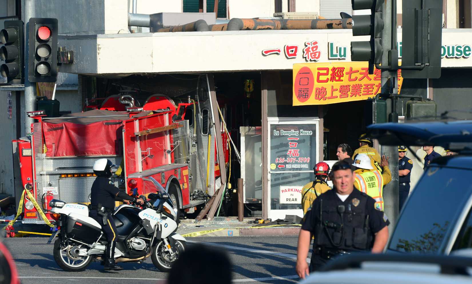 A motorcycle policeman arrives on the scene in Monterey Park, California on April 16, 2014, where two fire engines - one from the Monterey Park Fire department, another from the Alhambra Fire Department - chasing a fire crashed into each other with one barreling into a business, the Lu Dumpling House, leaving fifteen people injured.
