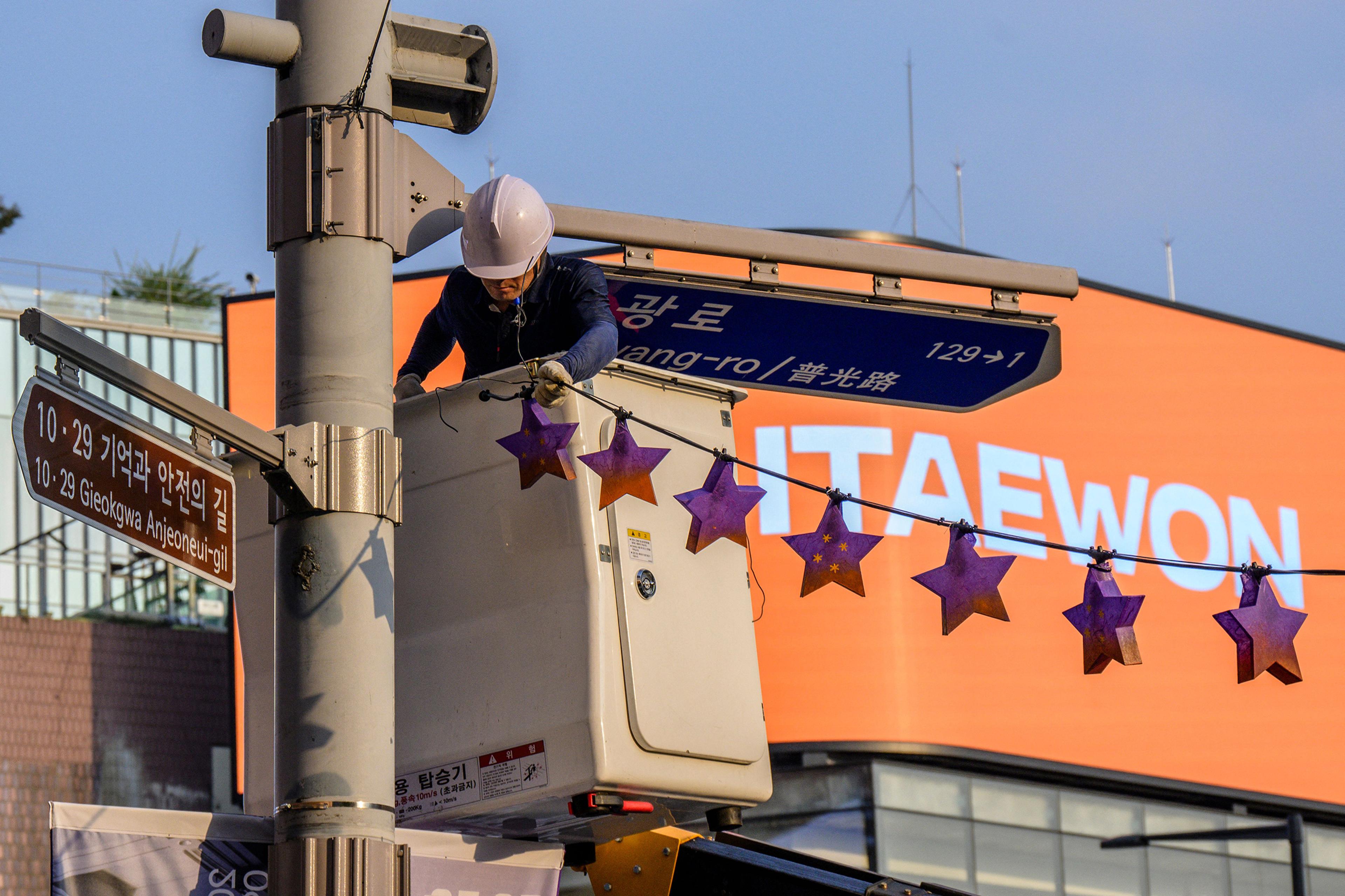 A worker displays star shaped lanterns in memory of victims of the Oct. 29 crowd crush that killed more than 150 people last Halloween, near the site of the tragedy in Itaewon, Seoul, on Oct. 25, 2023.