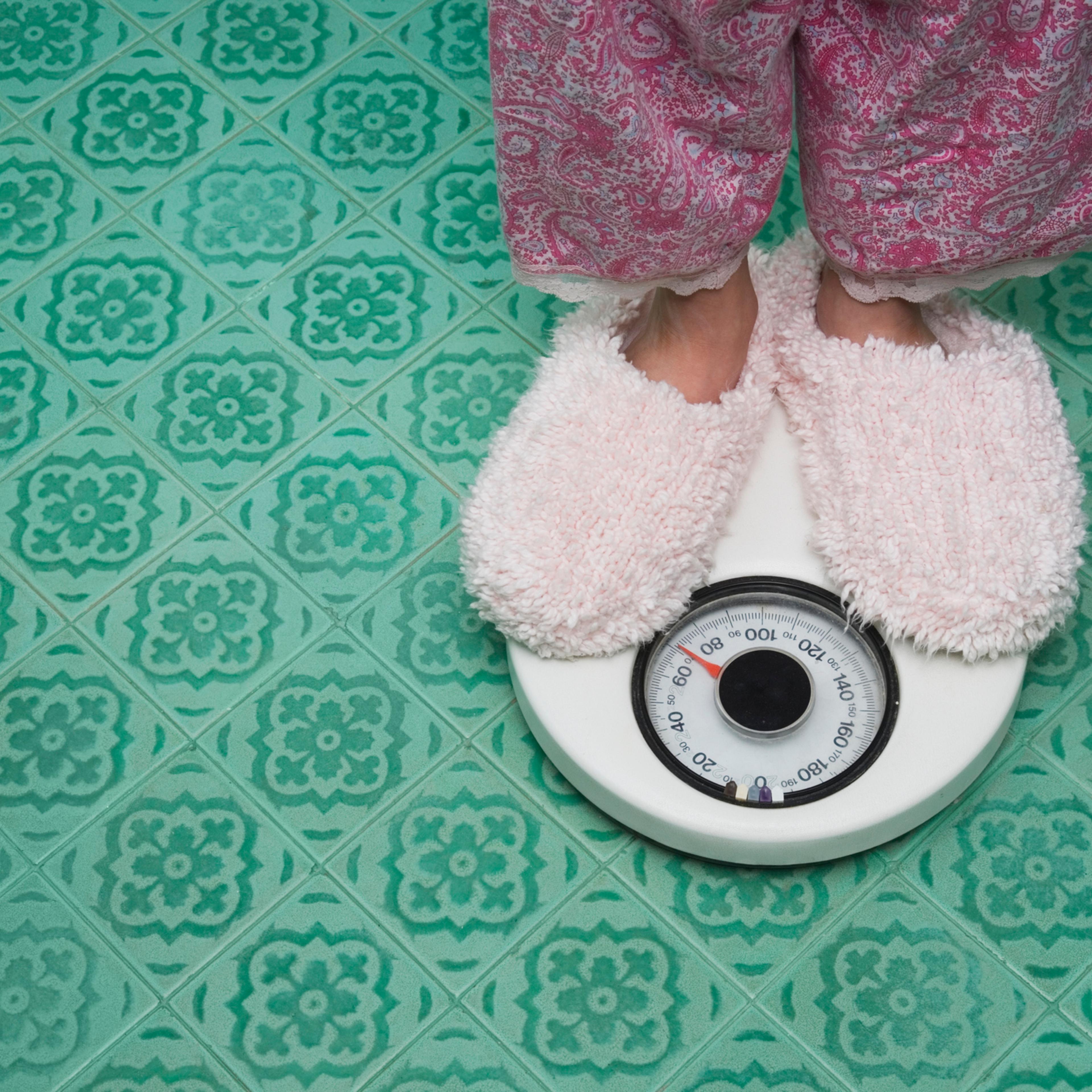Close up of feet in slippers on bathroom scale