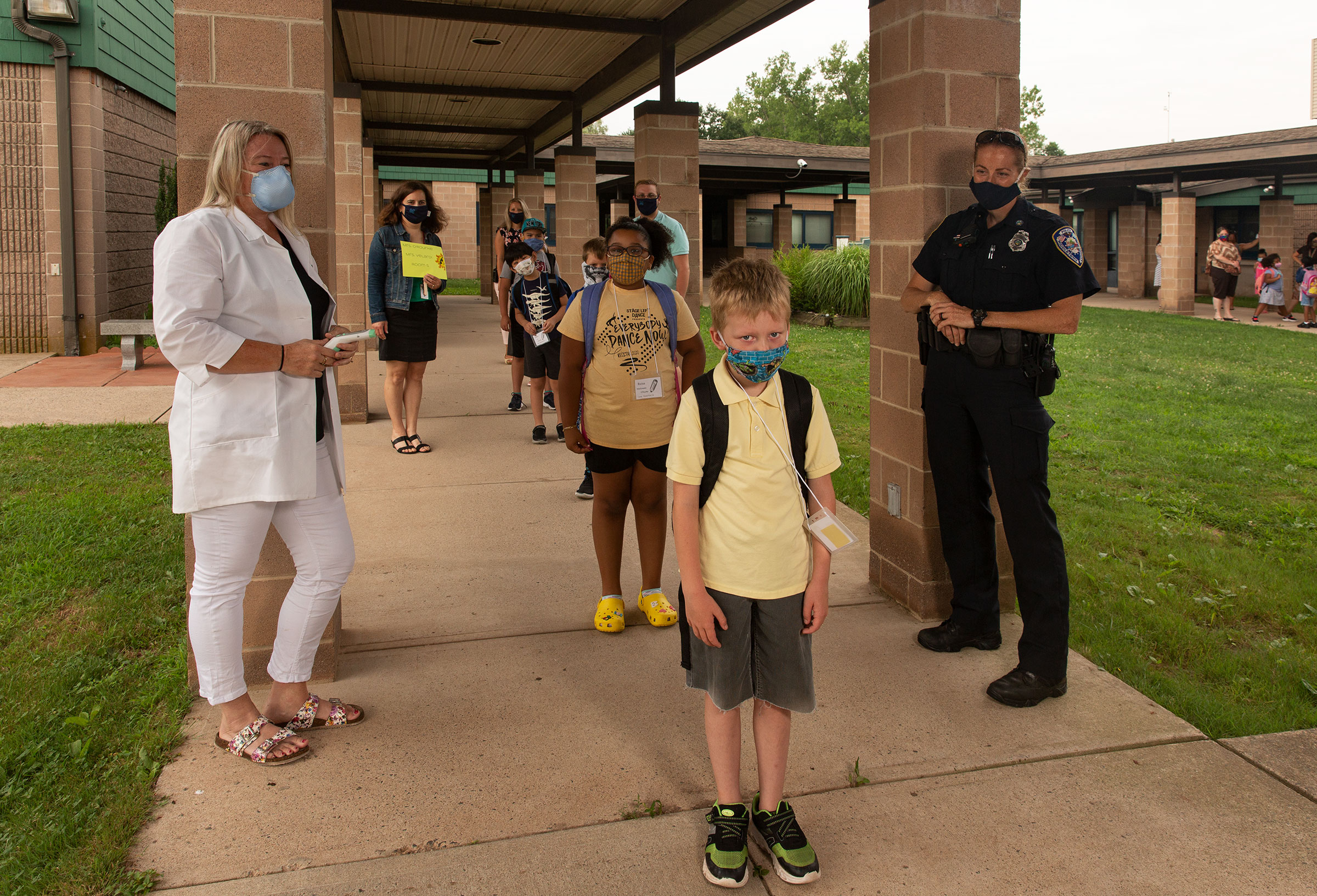 Nurse Sarah Ladd and school resource officer Kristen Tyrseck ensure kids keep a safe distance apart as they enter Wesley Elementary School in MIddletown, Conn.