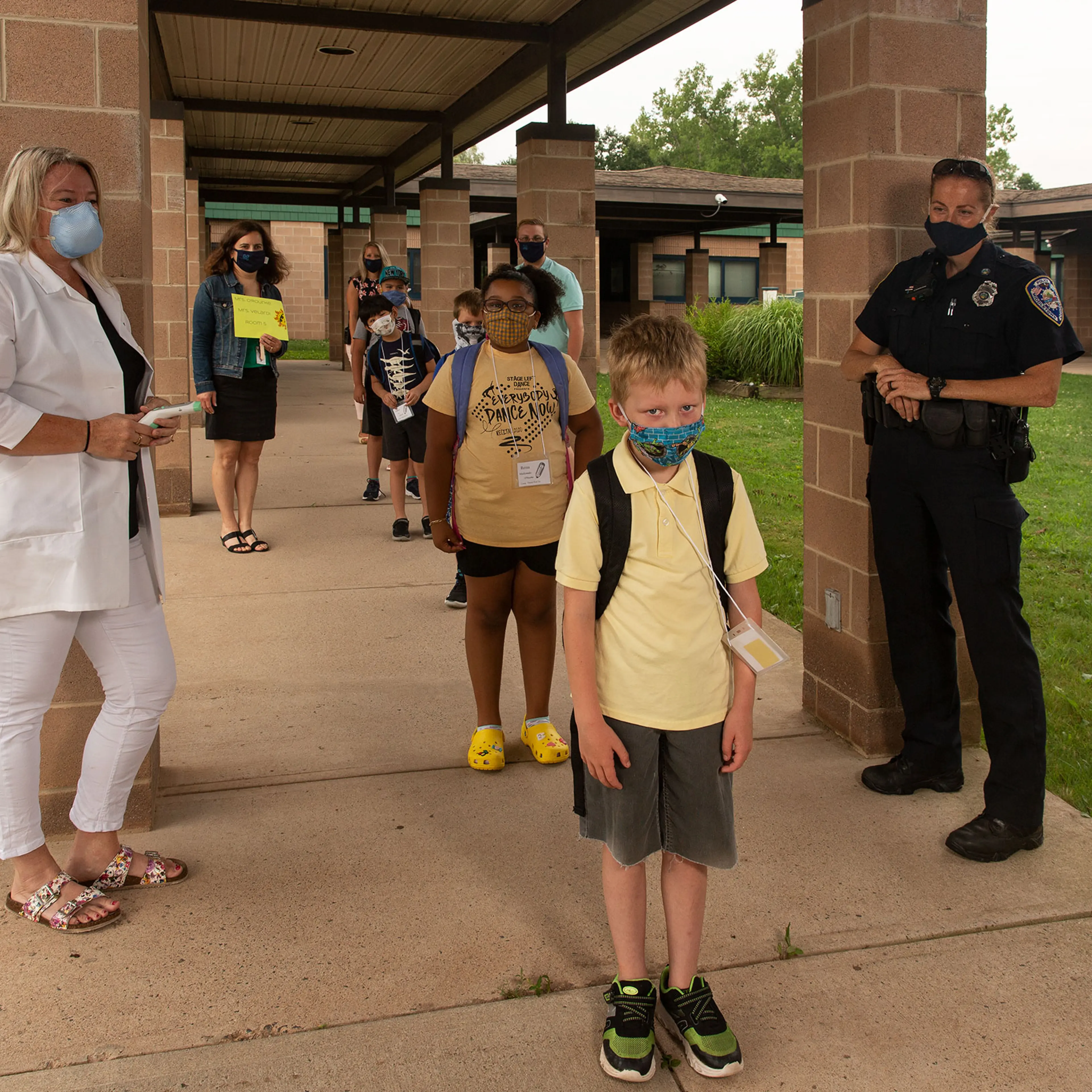 Nurse Sarah Ladd and school resource officer Kristen Tyrseck ensure kids keep a safe distance apart as they enter Wesley Elementary School in MIddletown, Conn.