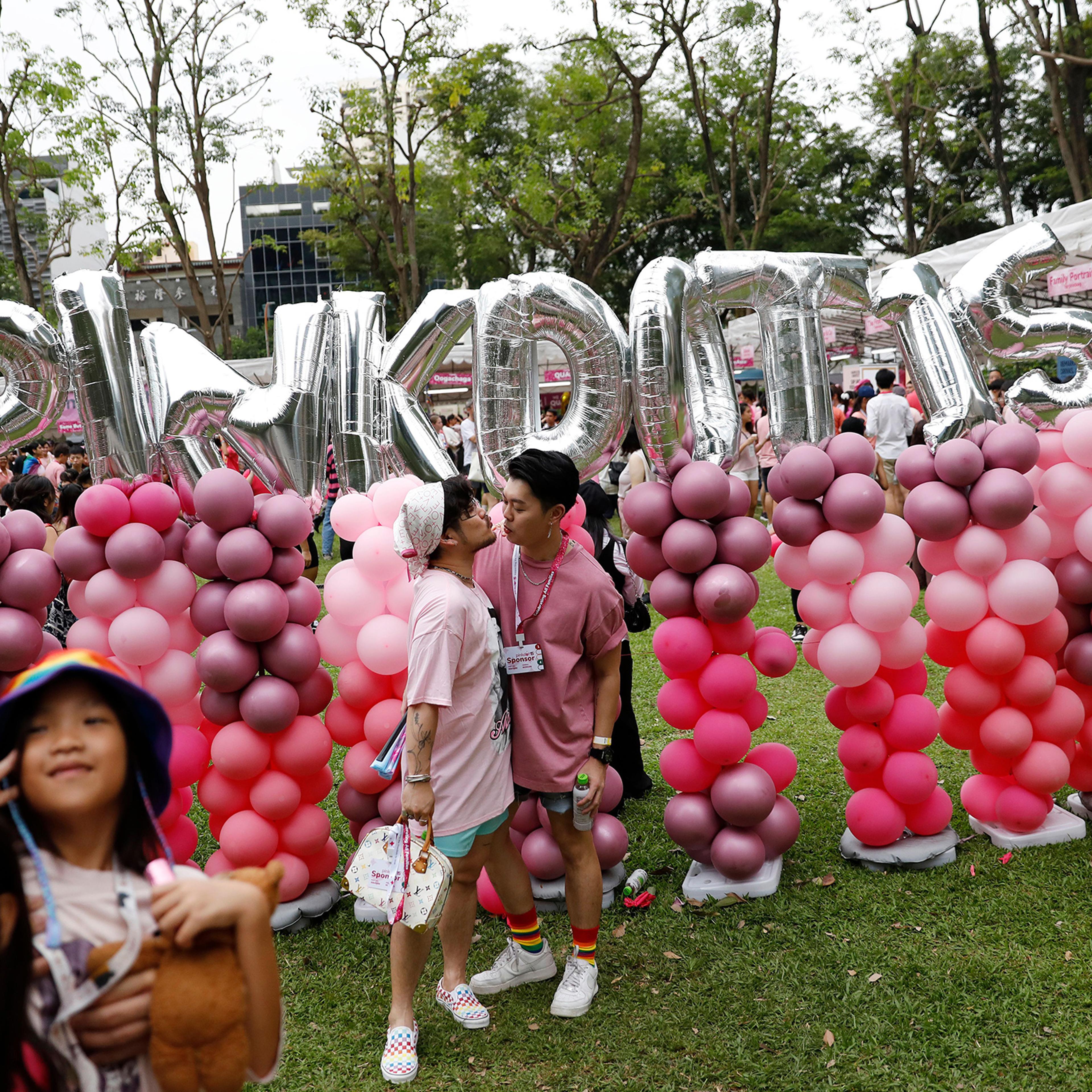 Pink Dot attendees pose for photos near balloons at Hong Lim Park in Singapore on June 24, 2023.