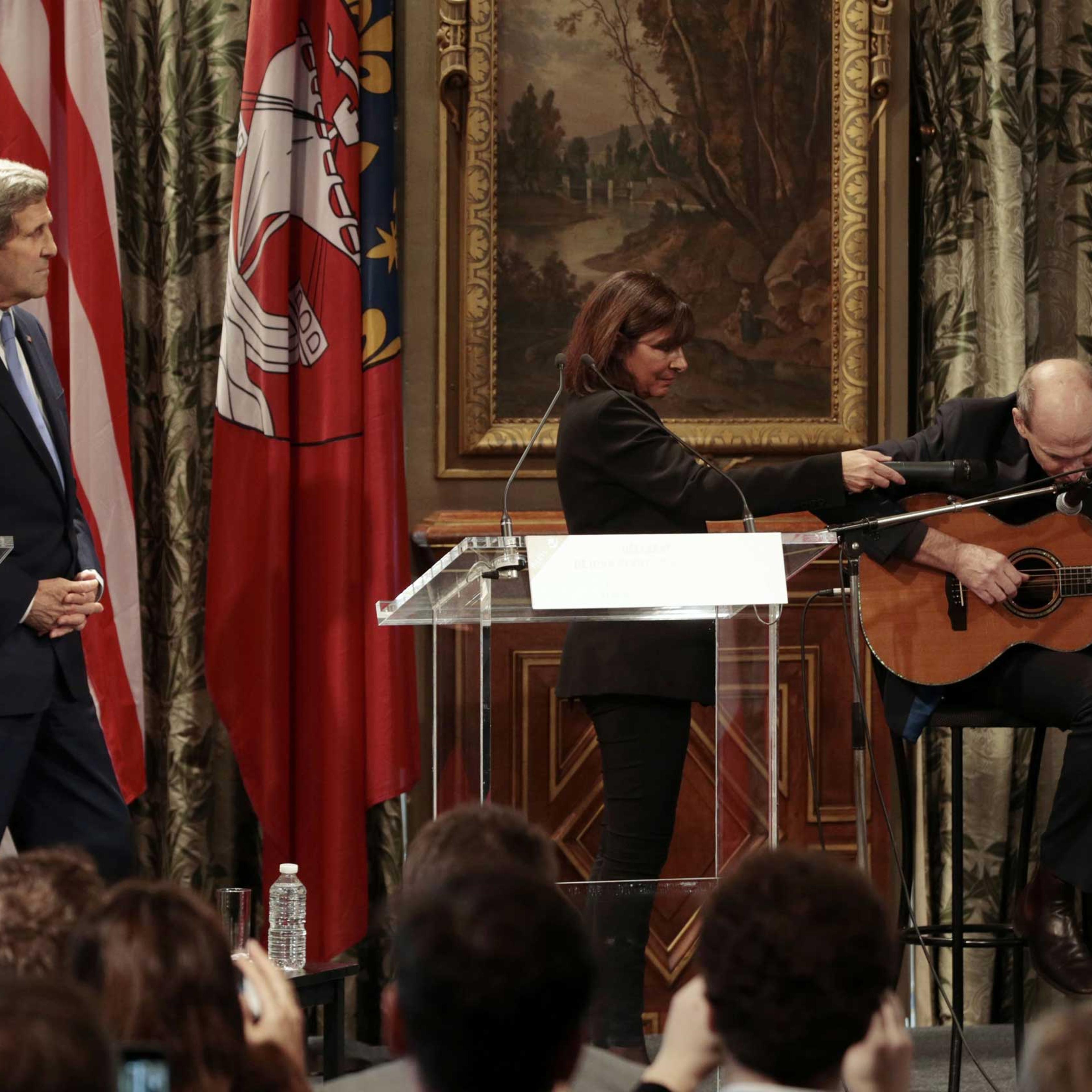 Paris Mayor Anne Hidalgo (C) and US Secretary of State John Kerry (L) listen to US musician James Taylor at Paris City Hall on January 16, 2015.