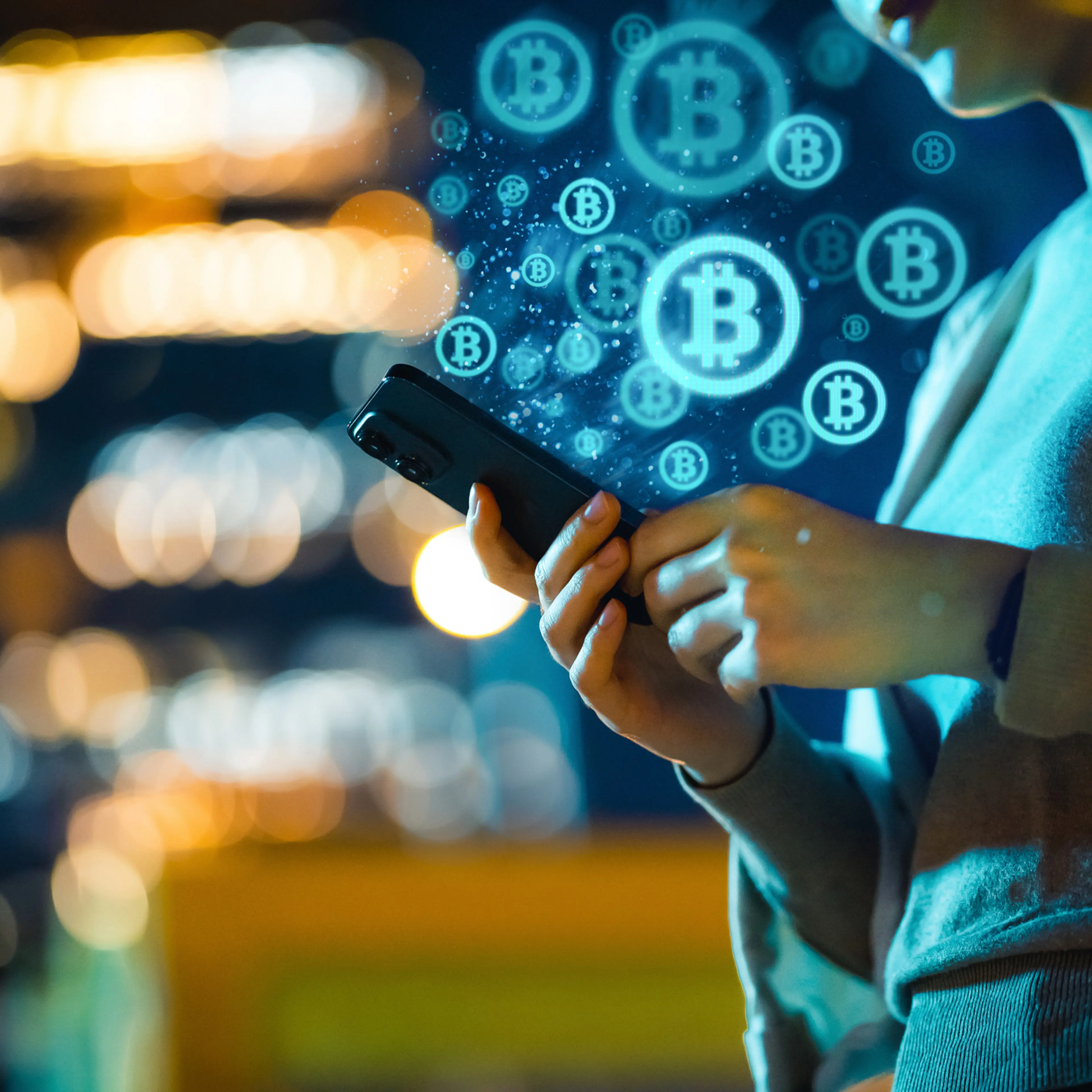 Mid-section of young Asian woman using smartphone in city at night, against illuminated street lights bokeh, working with Bitcoin technologies, investing or trading Bitcoin on cryptocurrency. Business on the go
