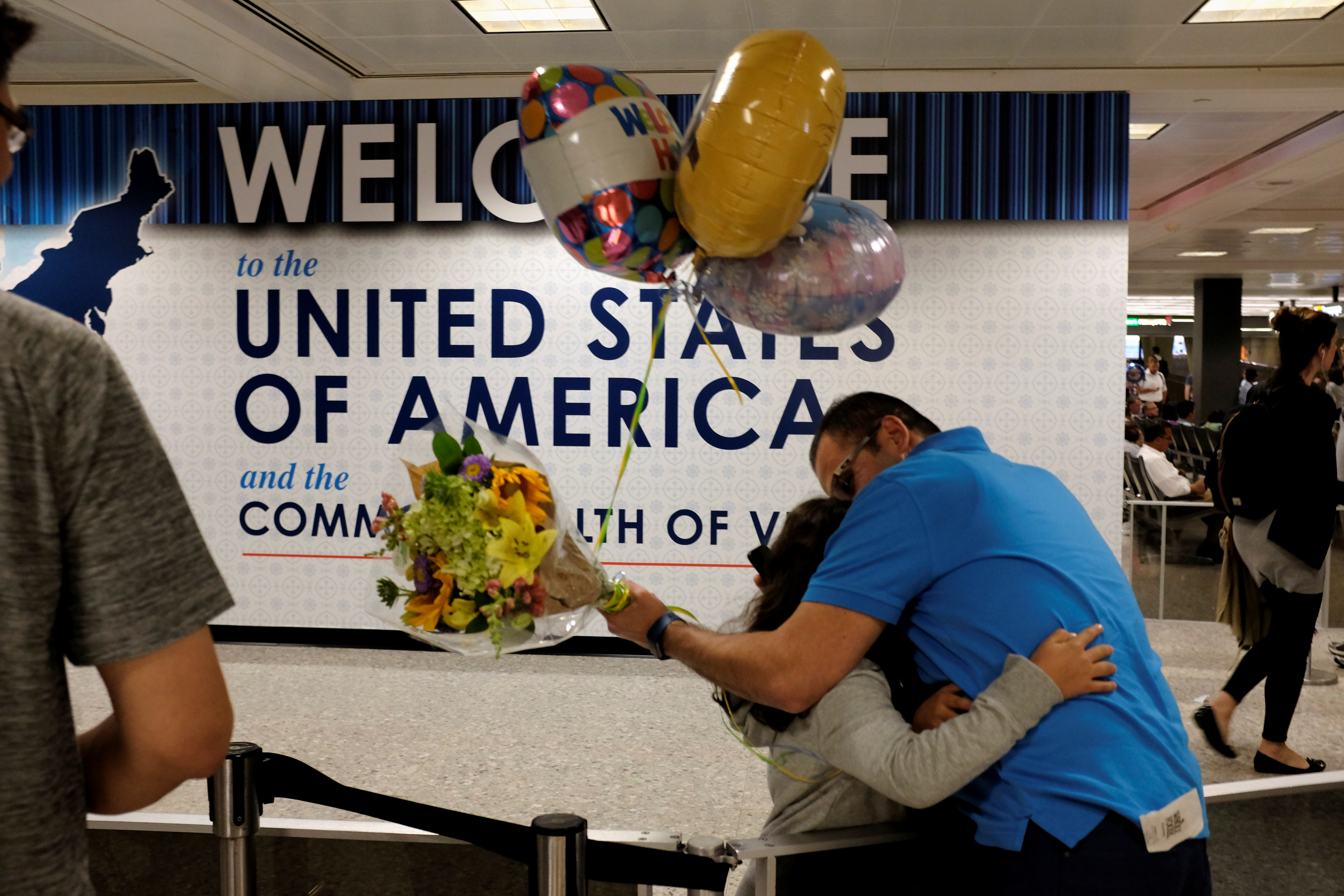 Ahmed Khalil, an Egyptian national residing in the United States, hugs his daughters as they arrive at Washington Dulles International Airport after the Trump administration's travel ban was allowed back into effect, in Dulles, Virginia