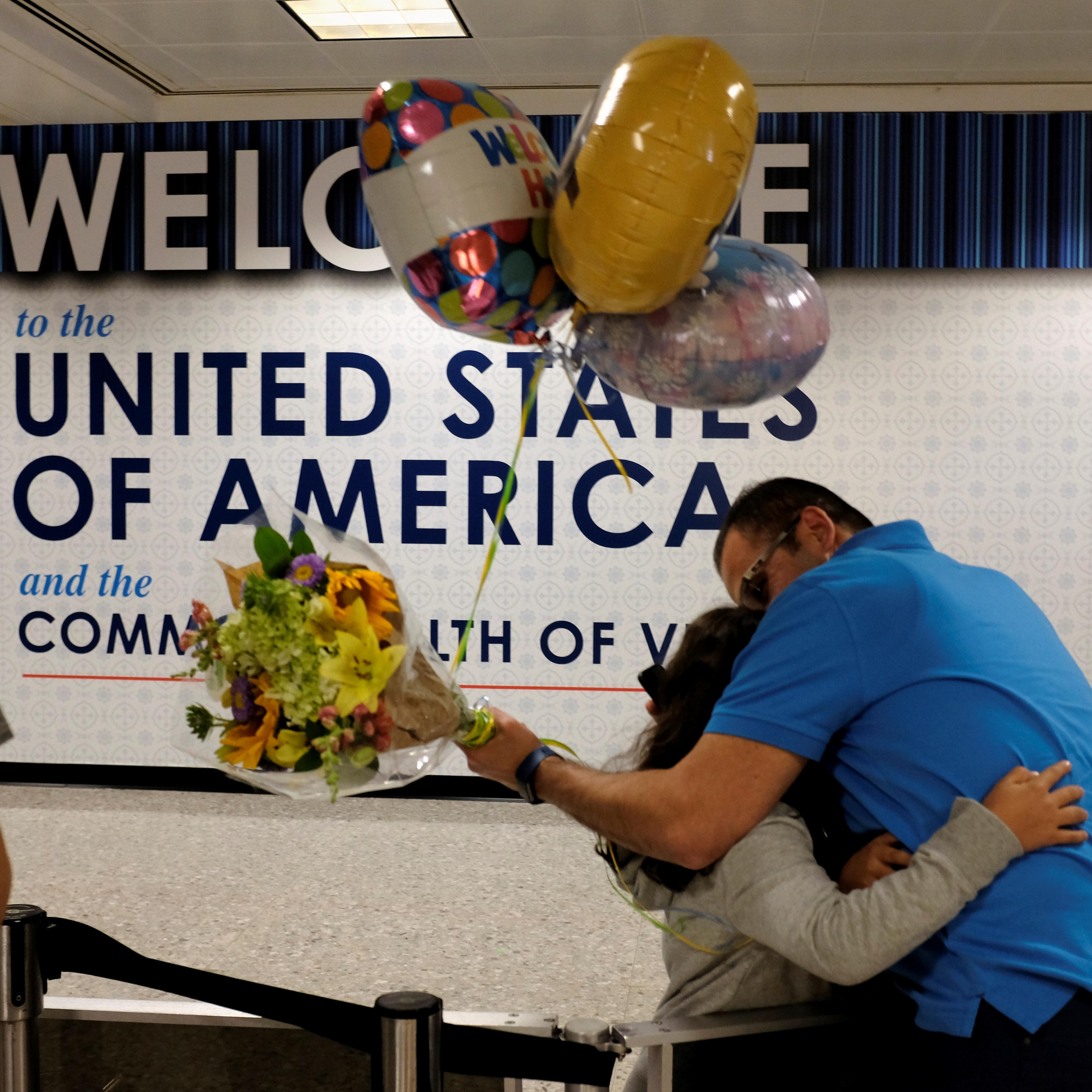 Ahmed Khalil, an Egyptian national residing in the United States, hugs his daughters as they arrive at Washington Dulles International Airport after the Trump administration's travel ban was allowed back into effect, in Dulles, Virginia