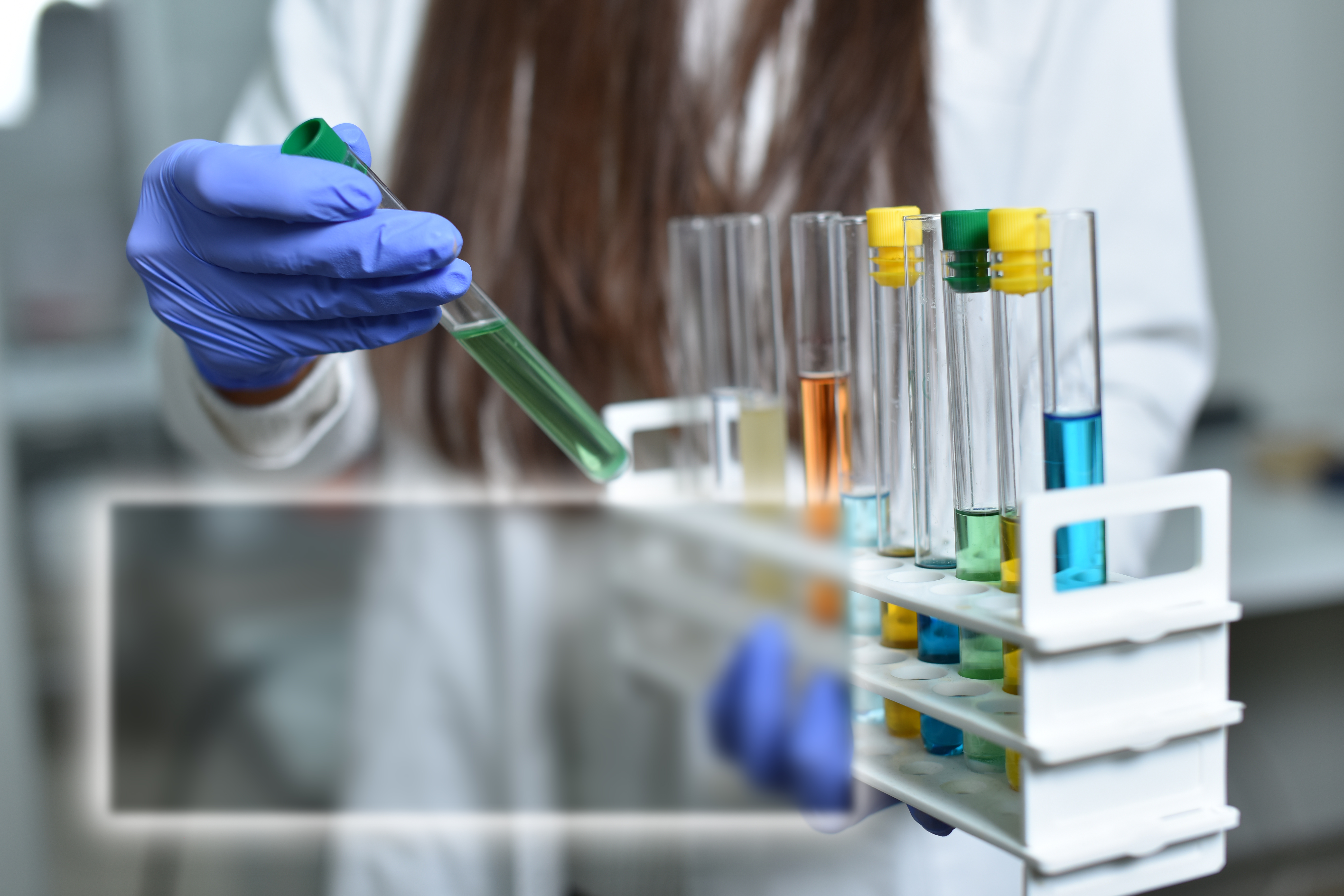 Female Scientist showing multi colored test tubes examples with space for text