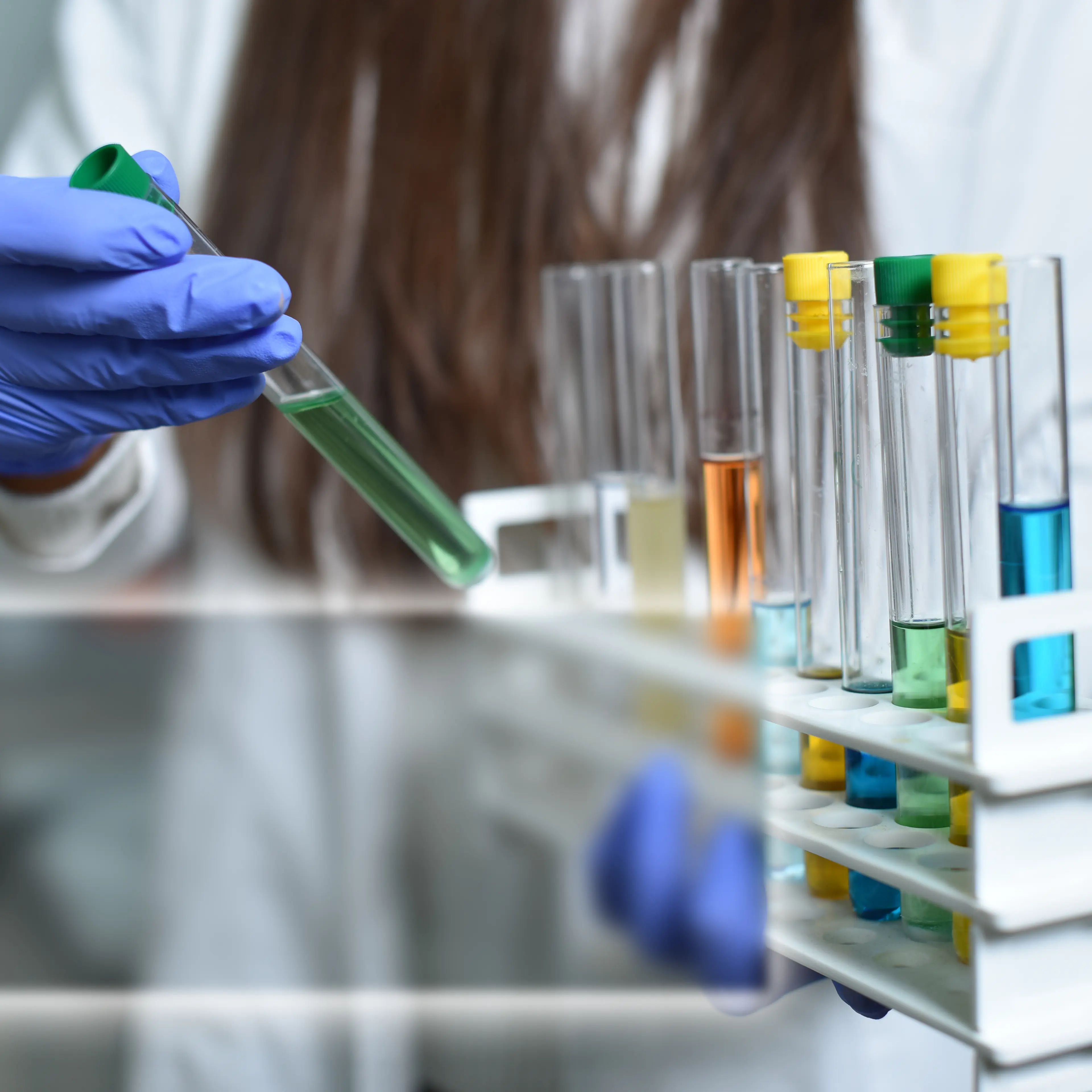 Female Scientist showing multi colored test tubes examples with space for text