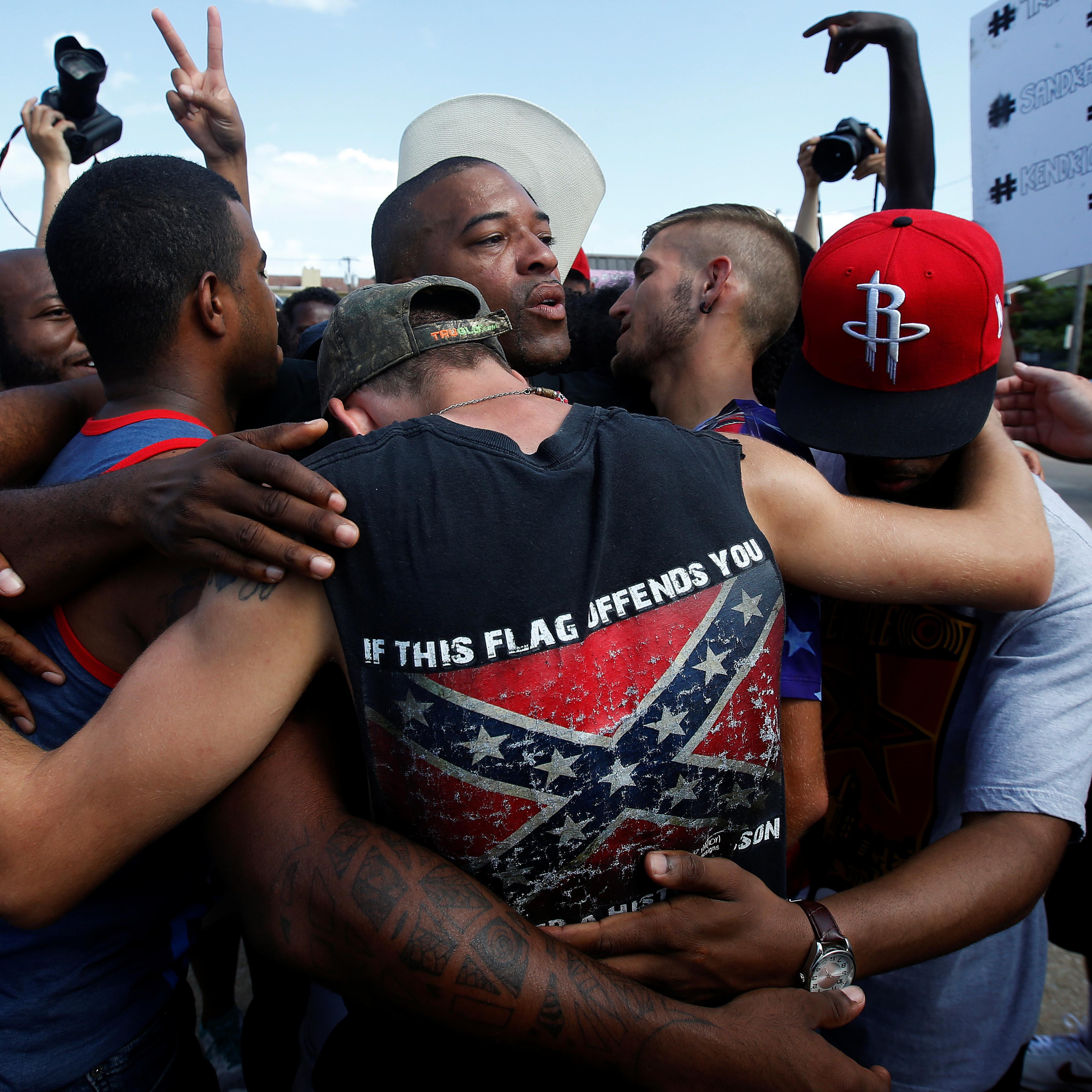 People, including a man wearing a confederate flag, hug after taking part in a prayer circle after a Black Lives Matter protest following the multiple police shootings in Dallas