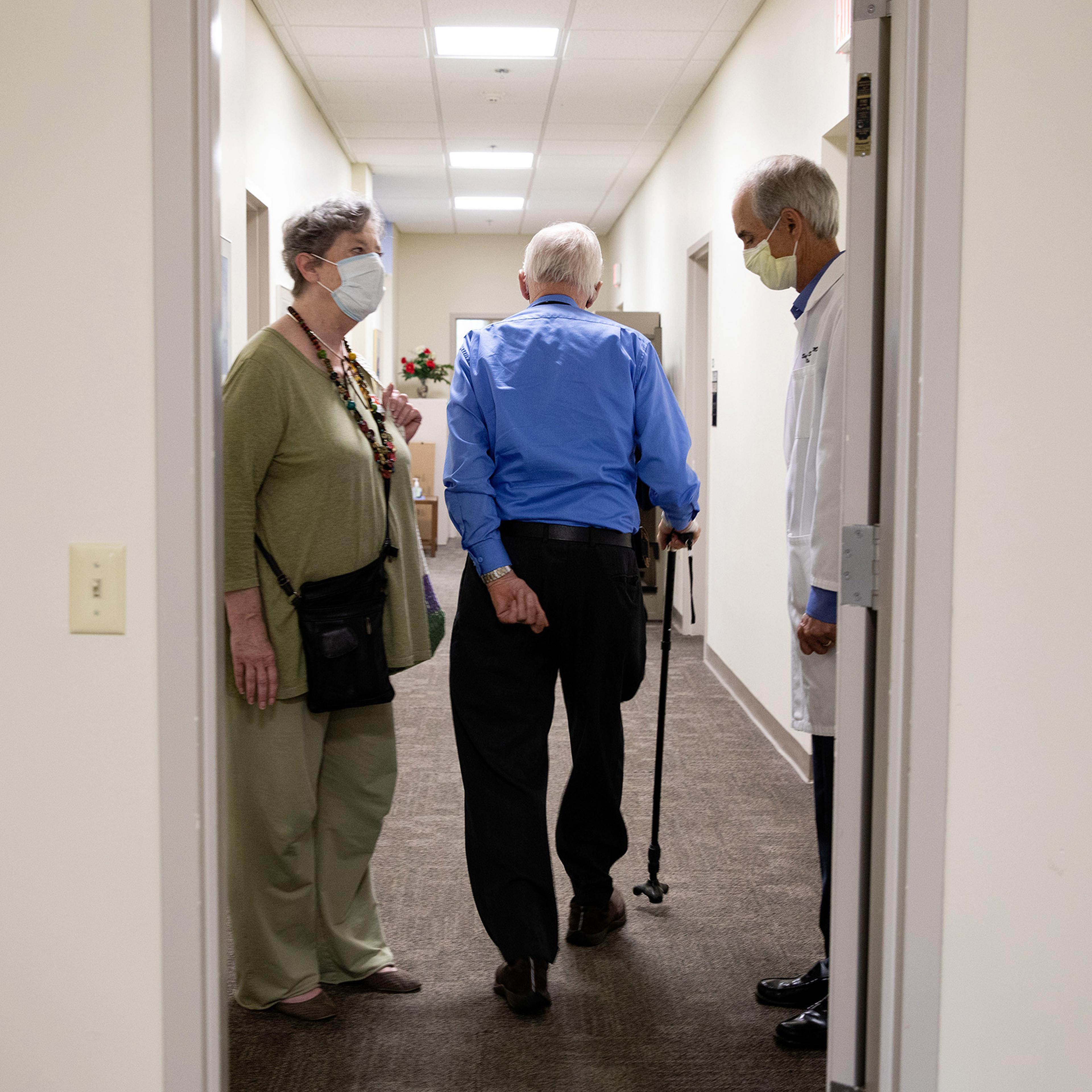 Henry Magendantz, center, a participant in the clinical trial of the experimental Alzheimer's drug, aducanumab, with his wife, Kathy Jellison, and Dr. Stephen Salloway, leaving the hospital after receiving an infusion in Providence, R.I., on May 27, 2021