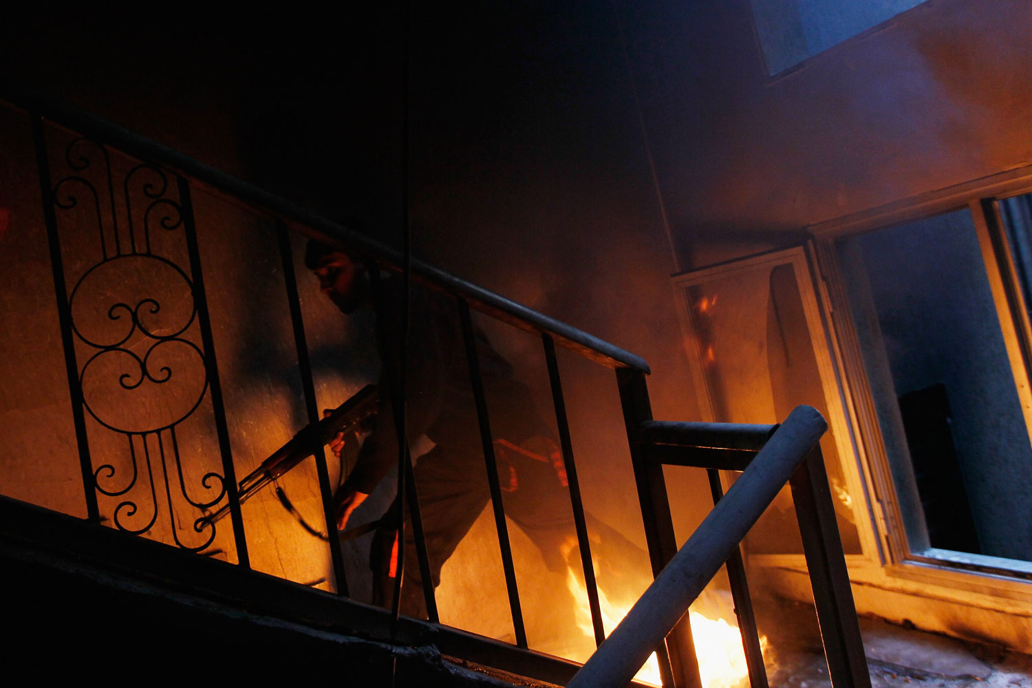 Misratah Libya April 20, 2011: A libyan rebel fighter runs up a burning stairwell during an effort to dislodge ensconced troops loyal to Moammar Gaddafi during house-to-house fighting on Tripoli Street in downtown Misratah, Libya.