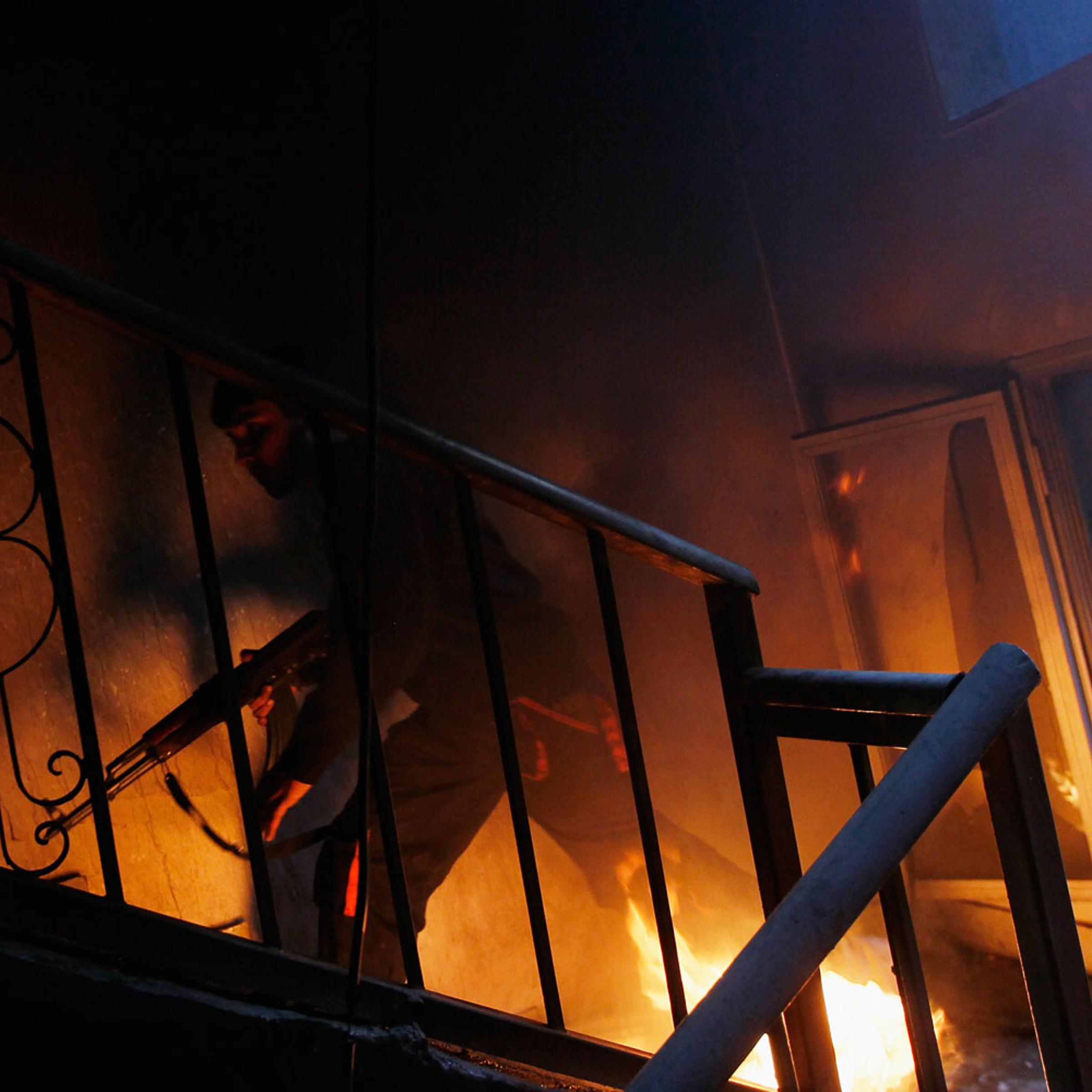 Misratah Libya April 20, 2011: A libyan rebel fighter runs up a burning stairwell during an effort to dislodge ensconced troops loyal to Moammar Gaddafi during house-to-house fighting on Tripoli Street in downtown Misratah, Libya.