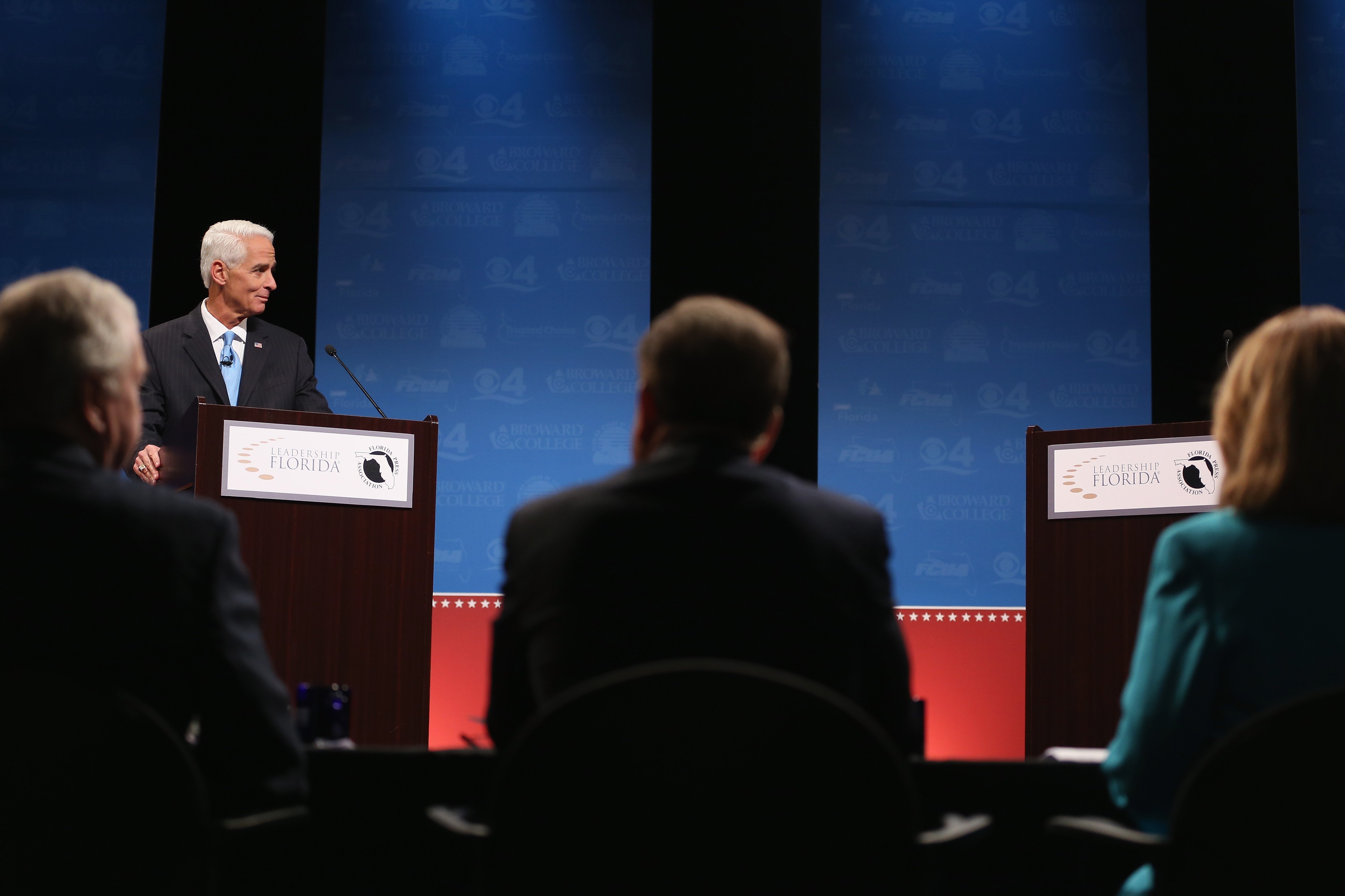 Former Florida Governor and Democratic candidate for Governor Charlie Crist waits next to an empty podium for Republican Florida Governor Rick Scott who delayed his entry onto the stage due to an electric fan that Crist had at his podium at a televised d