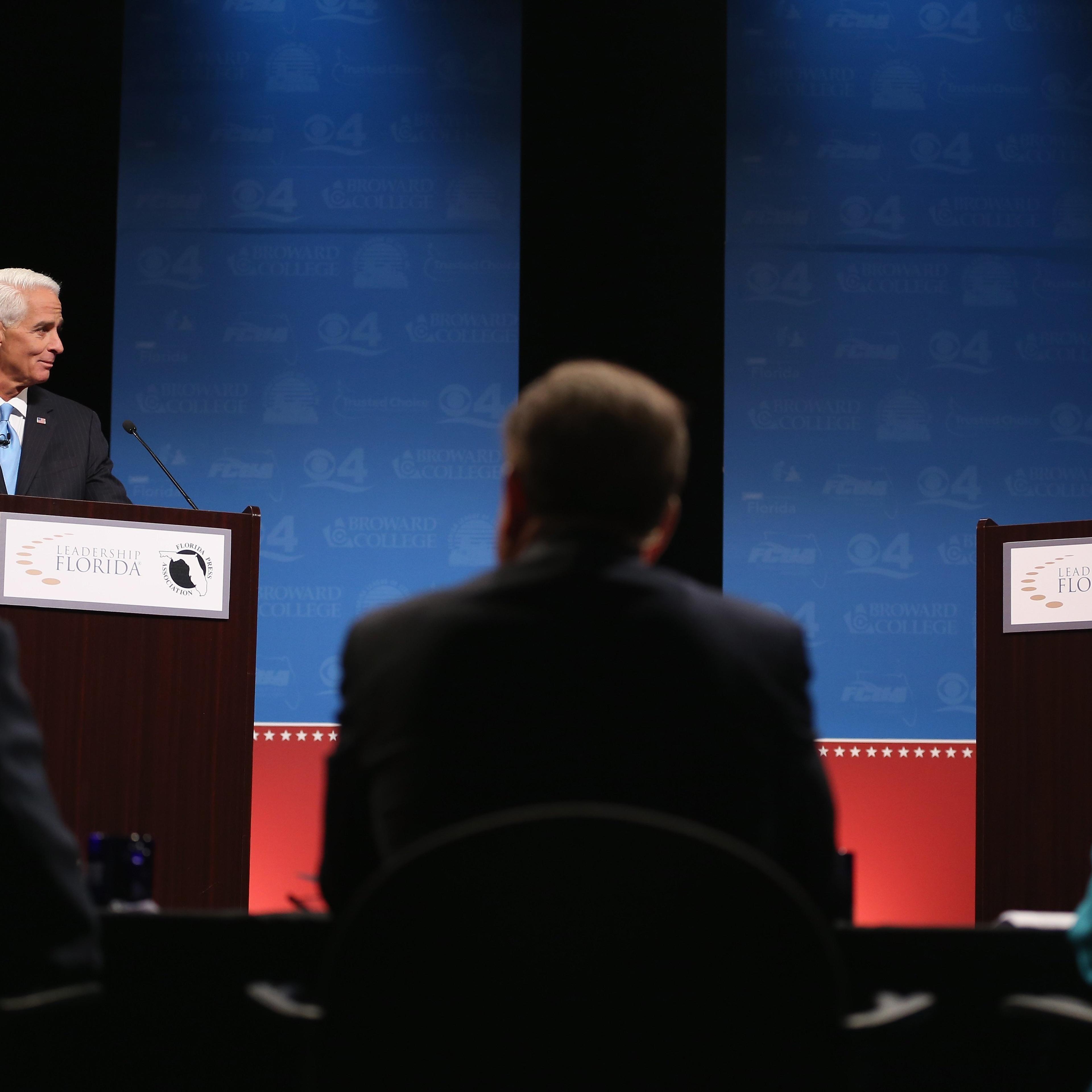 Former Florida Governor and Democratic candidate for Governor Charlie Crist waits next to an empty podium for Republican Florida Governor Rick Scott who delayed his entry onto the stage due to an electric fan that Crist had at his podium at a televised d