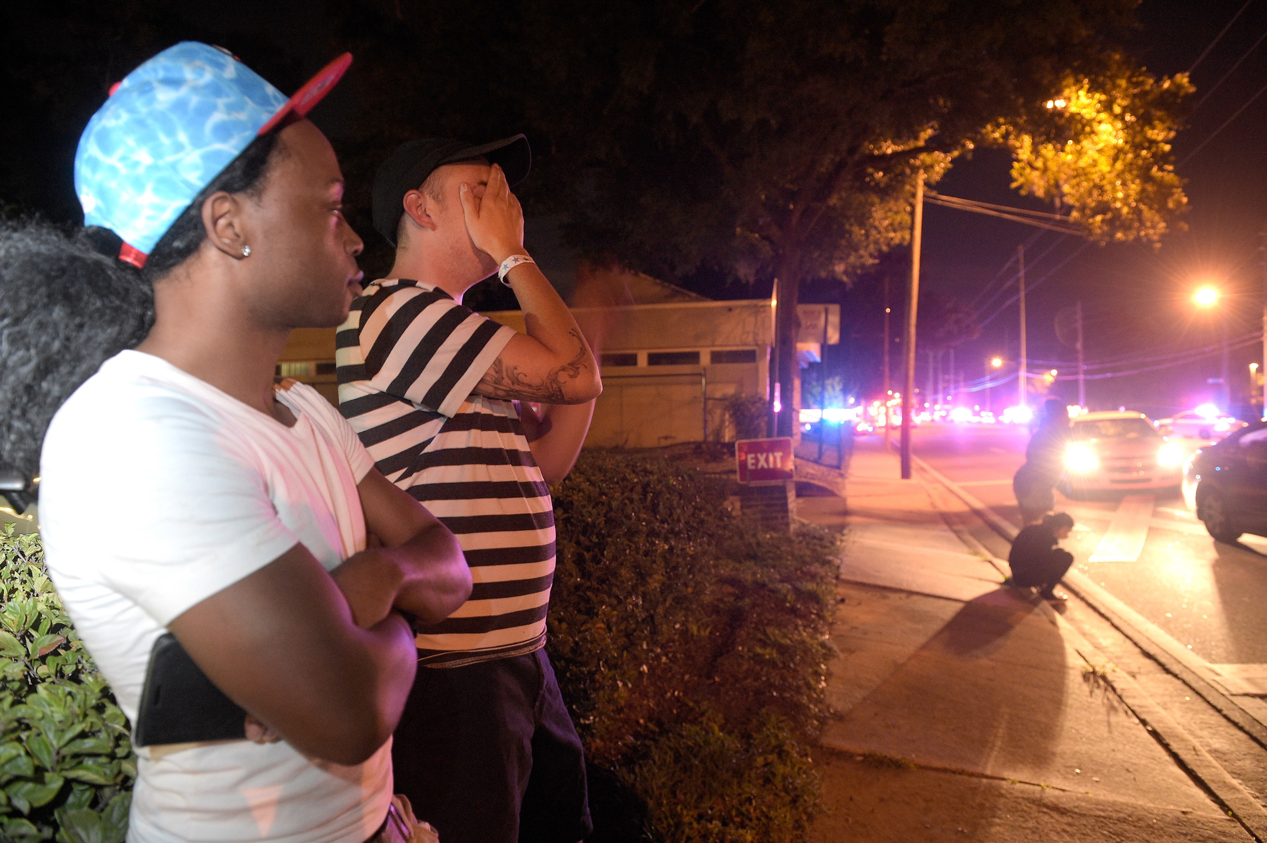 Jermaine Towns, left, and Brandon Shuford wait down the street from a multiple shooting at a nightclub in Orlando, Fla., Sunday, June 12, 2016. Towns said his brother was in the club at the time. A gunman opened fire at a nightclub in central Florida, an