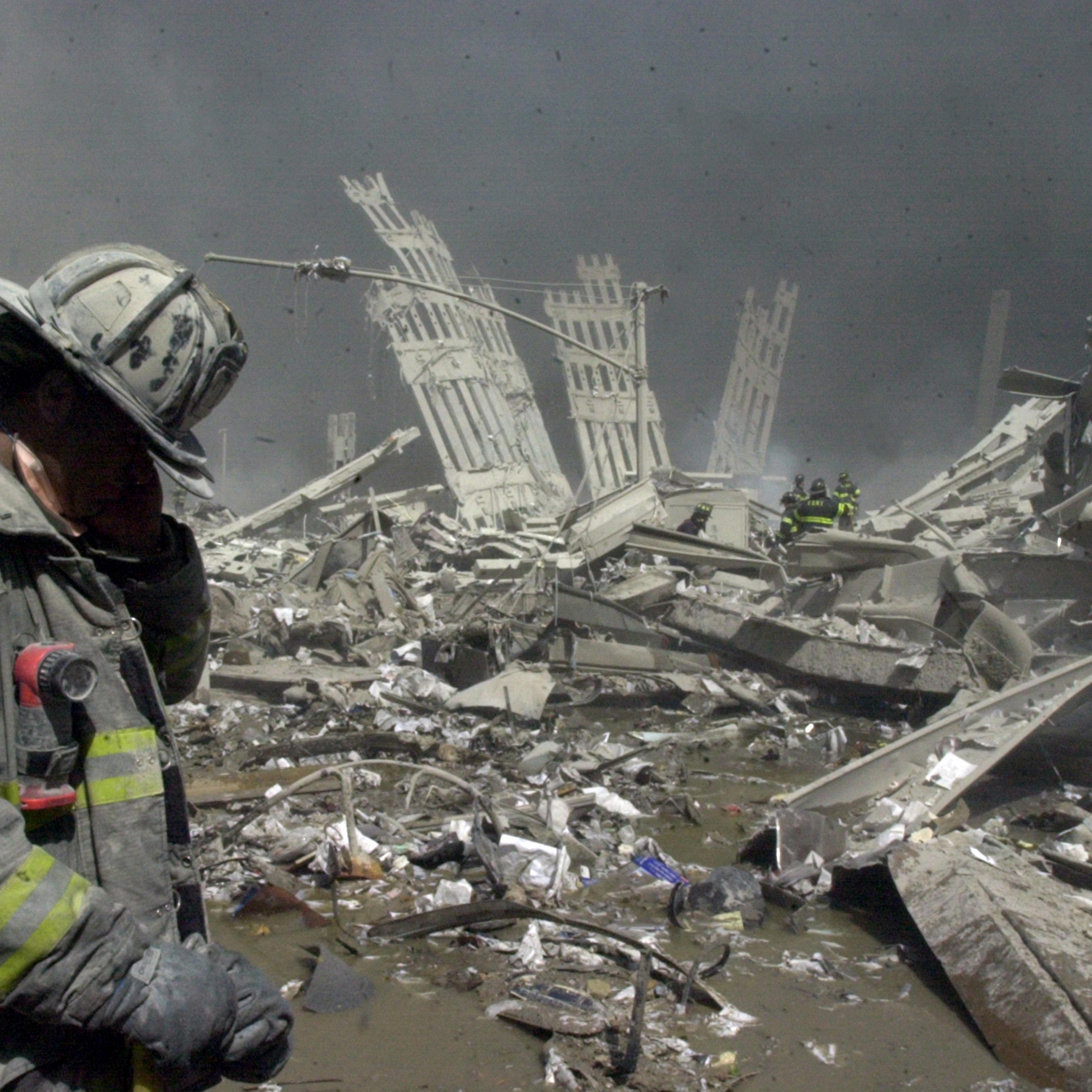 Firefighter walks through the rubble of the World Trade Center after it was struck by commercial airliners in a terrorist attack, Sept. 12 2001. after the first.