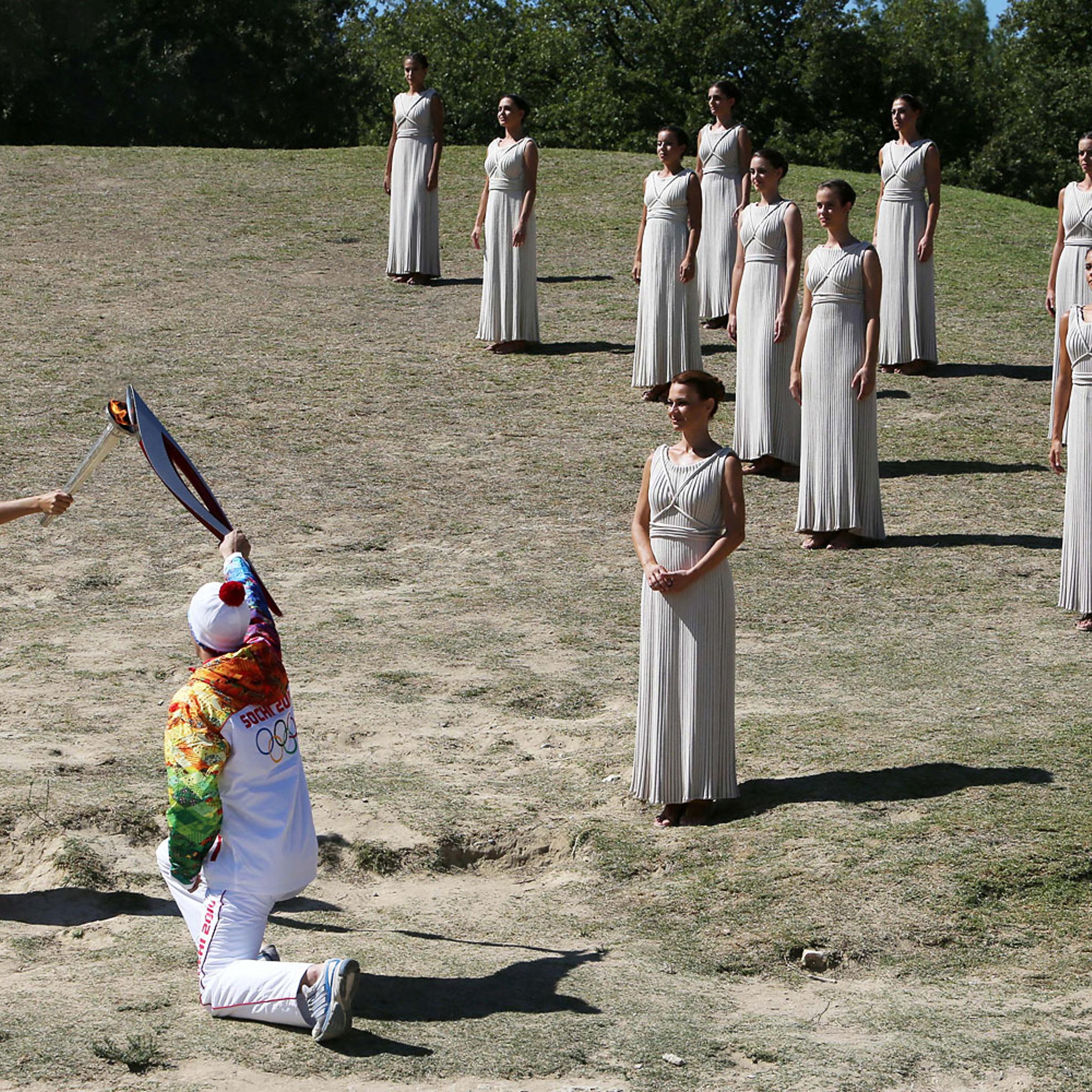 Actress Ino Menegaki as high priestess, left, passes the Olympic Flame to the first torch runner - Greek champion skier Giannis Antoniou - during the final dress rehearsal at Ancient Olympia, in west southern Greece.