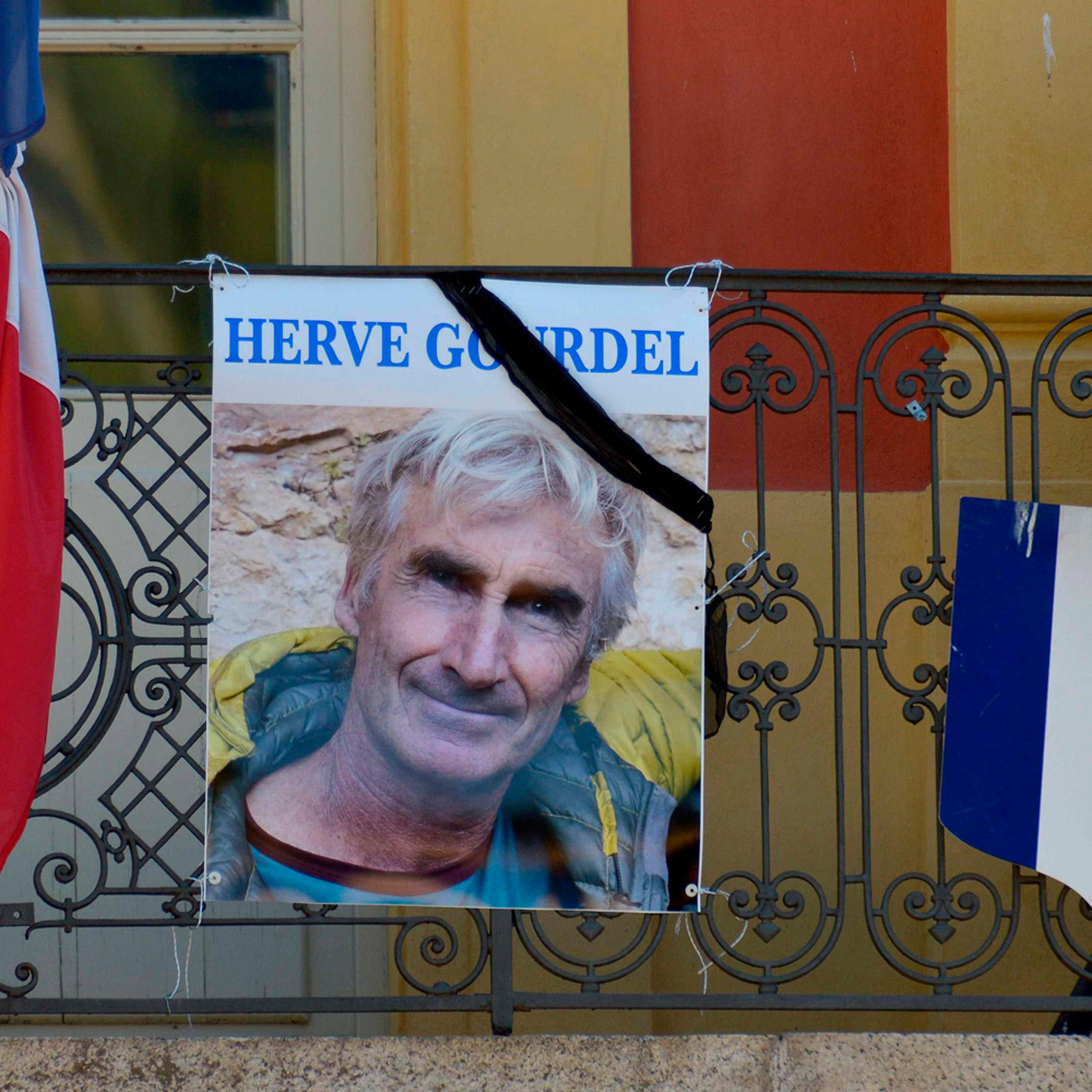 A portrait of mountain guide Frenchman Herve Gourdel hangs near a French flag outside the town hall in Saint-Martin-Vesubie, Sept. 25, 2014.