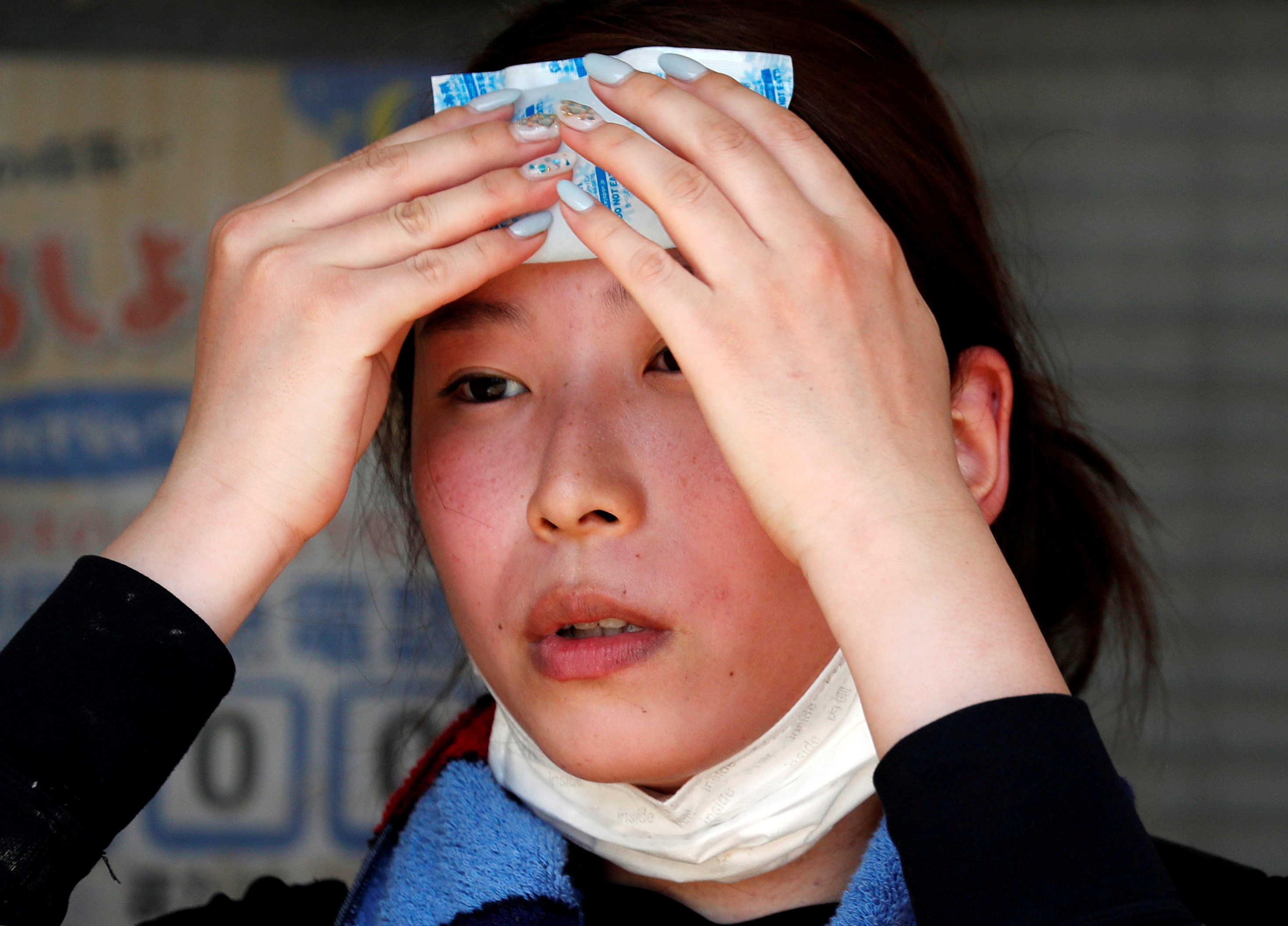 FILE PHOTO: A volunteer, for recovery work, uses a pack of refrigerant to a cool down as she takes a break in a heat wave at a flood affected area in Kurashiki